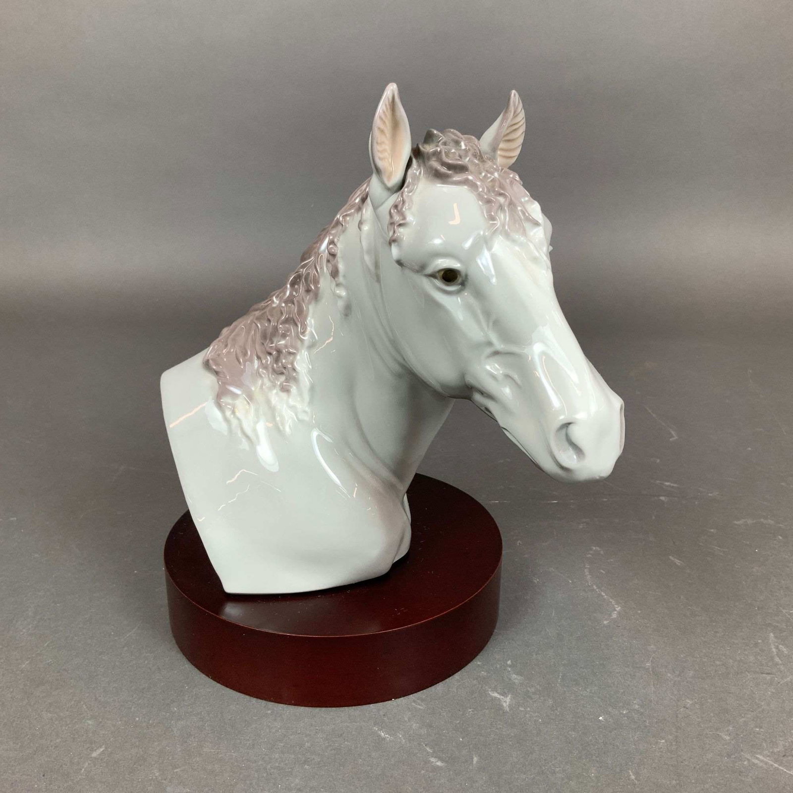 Lladro Porcelain Bust on Base, Derby Winner Horse 01005544: This Lladro porcelain figurine, titled Derby Winner (Item 01005544), depicts the bust of a horse. The piece is crafted from glazed porcelain and features a high-gloss white finish on the head and neck