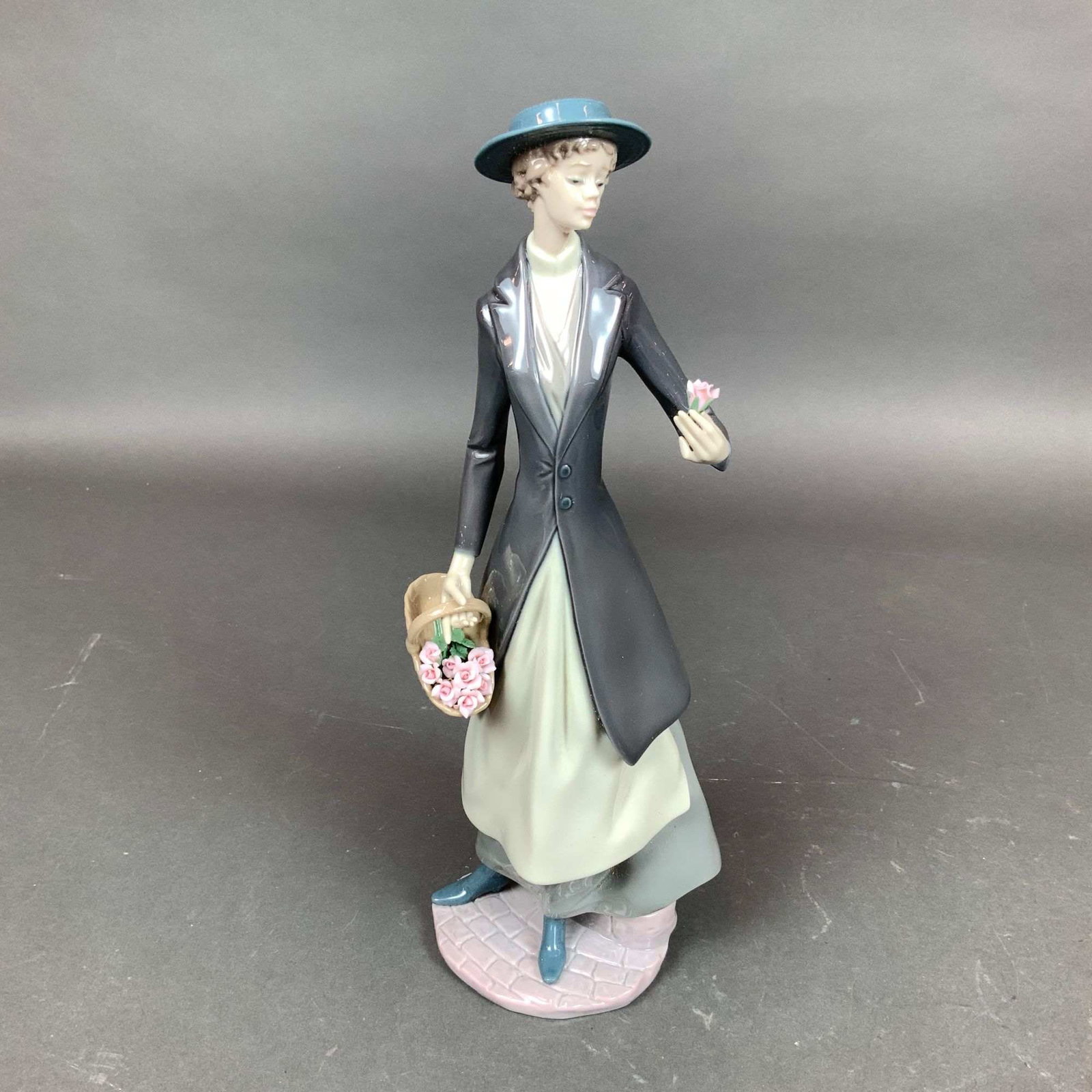 Lladro Glazed Porcelain Figurine, Tokens of Love 01006351: A hand-painted glazed porcelain figurine by Lladro titled Tokens of Love (Item #01006351), originally designed by sculptor Juan Huerta. The piece depicts a slender woman in Edwardian-style attire, inc