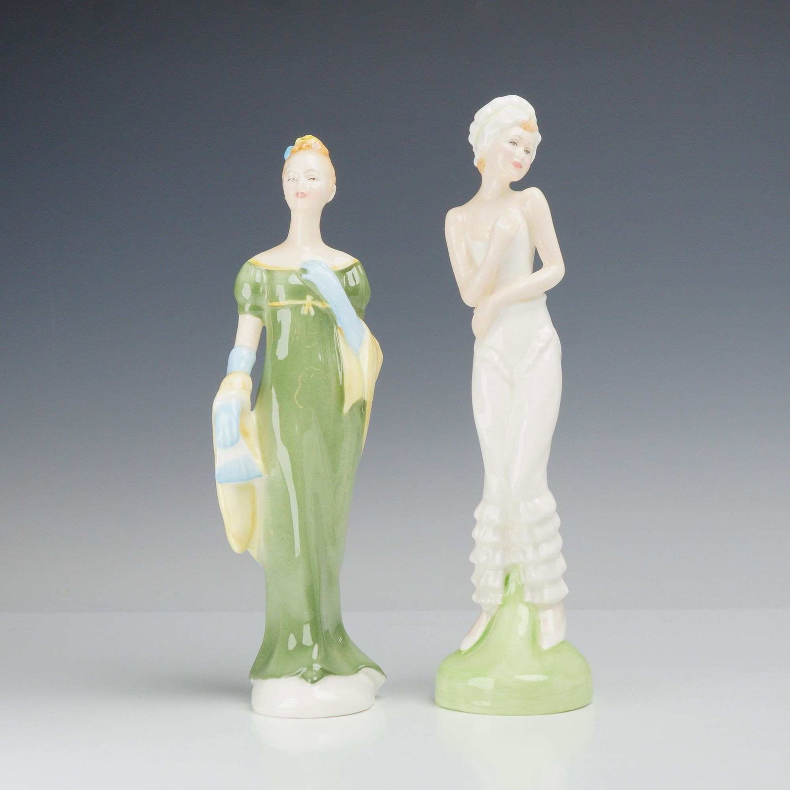 2pc Royal Doulton Figurines, Lorna and Modesty: This lot features two glazed bone china figurines manufactured by Royal Doulton of England. The first figurine, titled Lorna (HN 2311), depicts a woman in a green Regency style empire waist gown with 