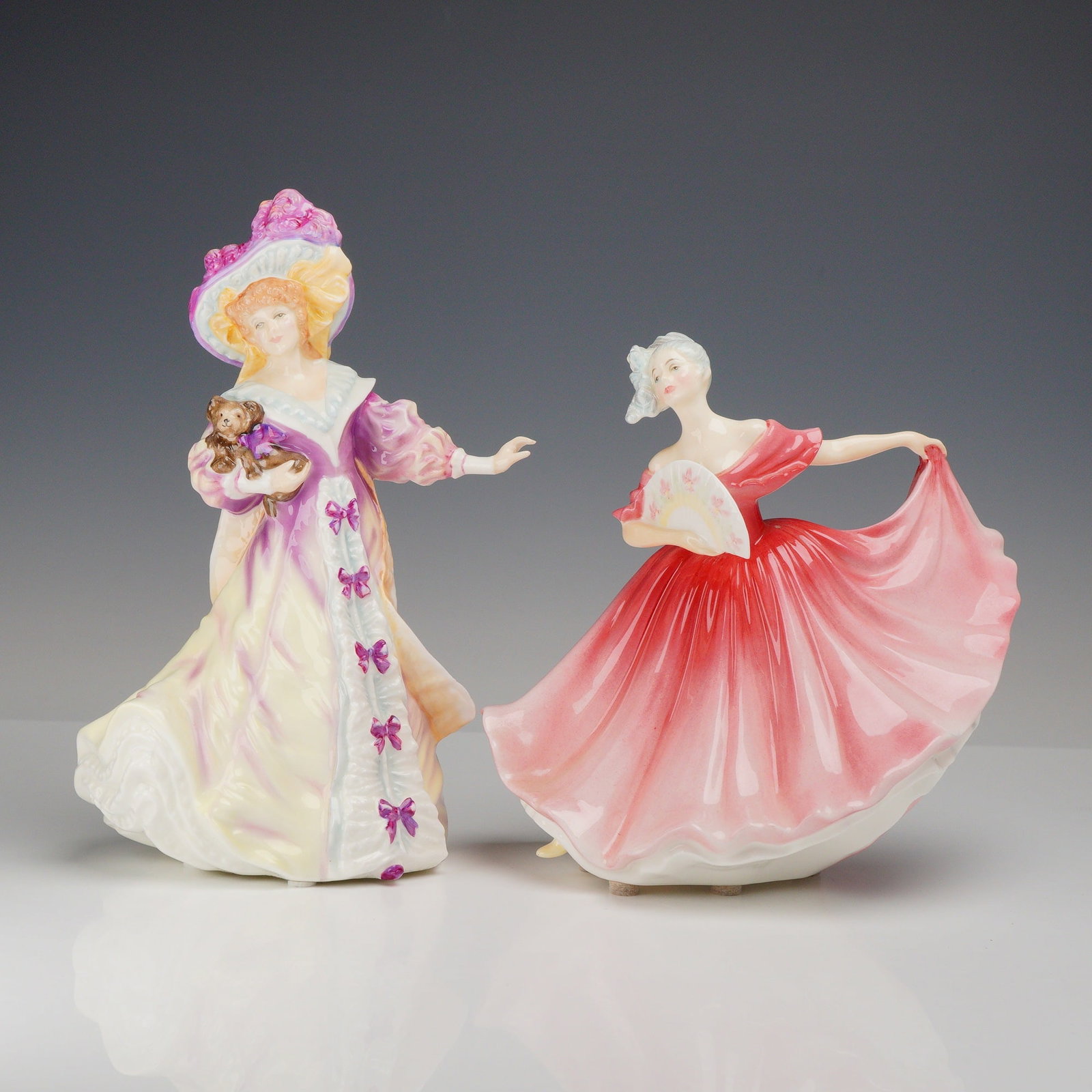 2pc Royal Doulton Glazed Bone China Figurines Lily HN 3626 and Elaine HN 3307: This lot features a pair of Royal Doulton polychrome glazed bone china figurines titled Lily and Elaine. The figurine Lily, model HN 3626, depicts a woman in an elaborate late Victorian or Edwardian s