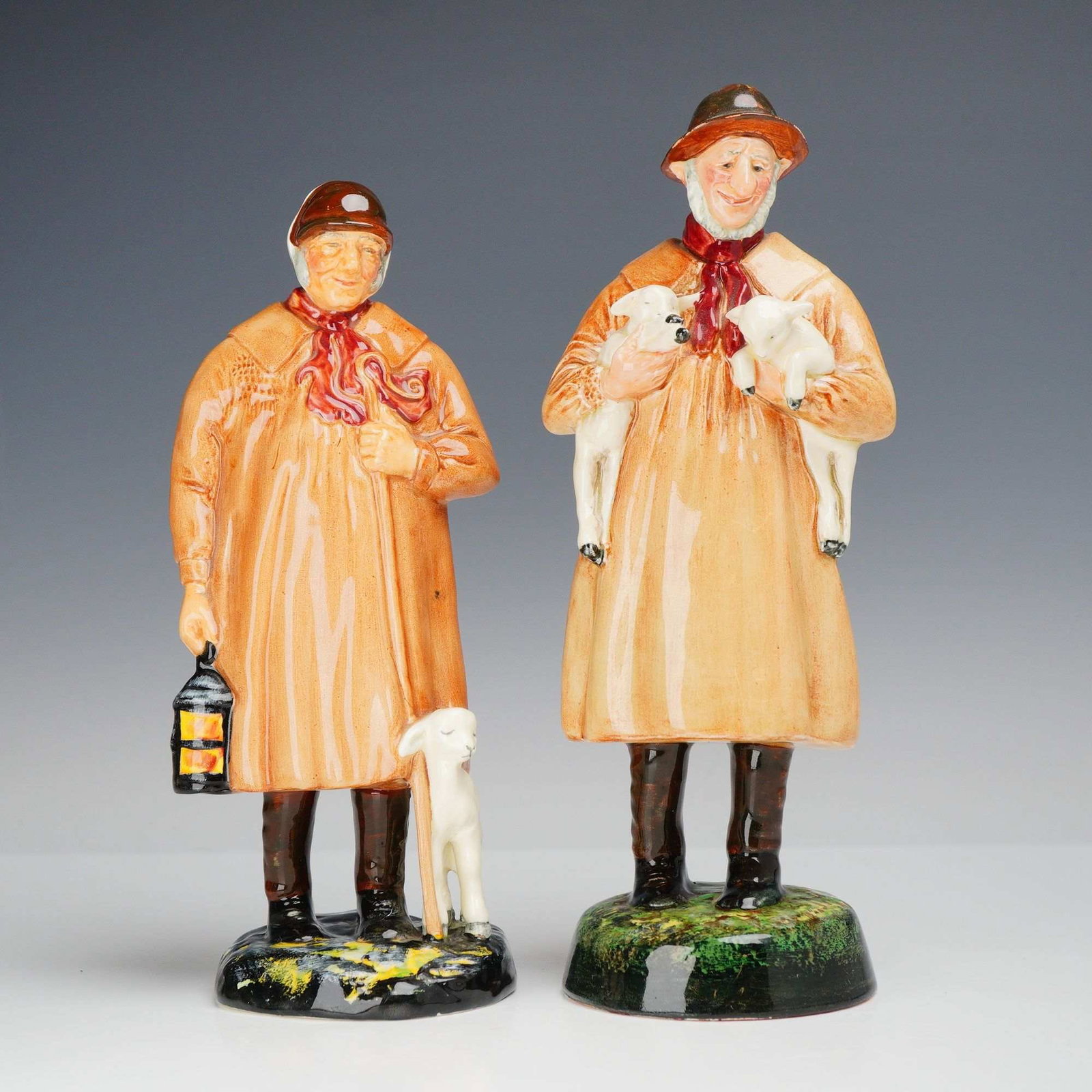 2pc Royal Doulton Porcelain Figurines, The Shepherd HN1975 and Lambing Time HN1890: A pair of glazed porcelain figurines produced by Royal Doulton, featuring the titles The Shepherd and Lambing Time. Both pieces depict rustic country shepherds in traditional attire, characterized by 