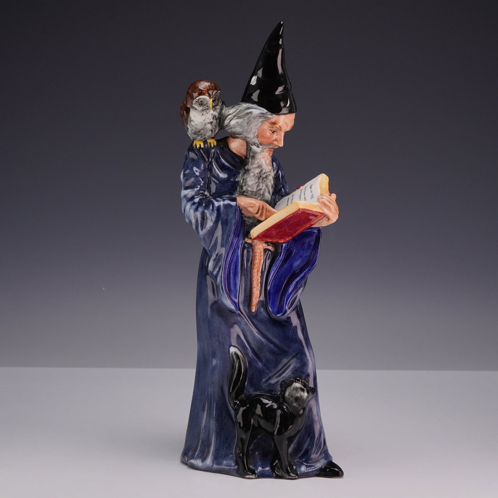 Royal Doulton The Wizard Figurine HN 2877: A Royal Doulton glazed porcelain figurine titled The Wizard, model number HN 2877. This hand-decorated figure depicts a wizard with a long grey beard and a black pointed hat featuring a white star. He