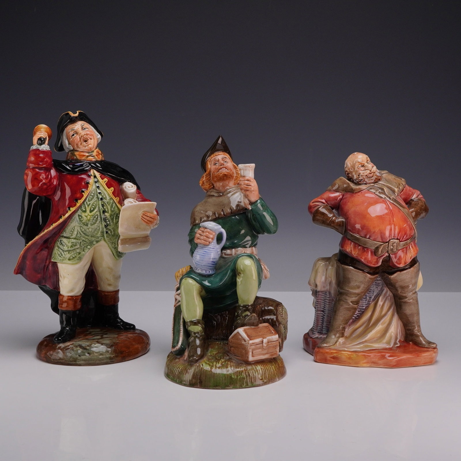 3pc Royal Doulton Character Figurines, Falstaff, Robin Hood, and Town Crier: This collection consists of three Royal Doulton polychrome glazed porcelain character figurines representing historical and literary figures finished in high-gloss glaze. The Town Crier HN 2119 depict