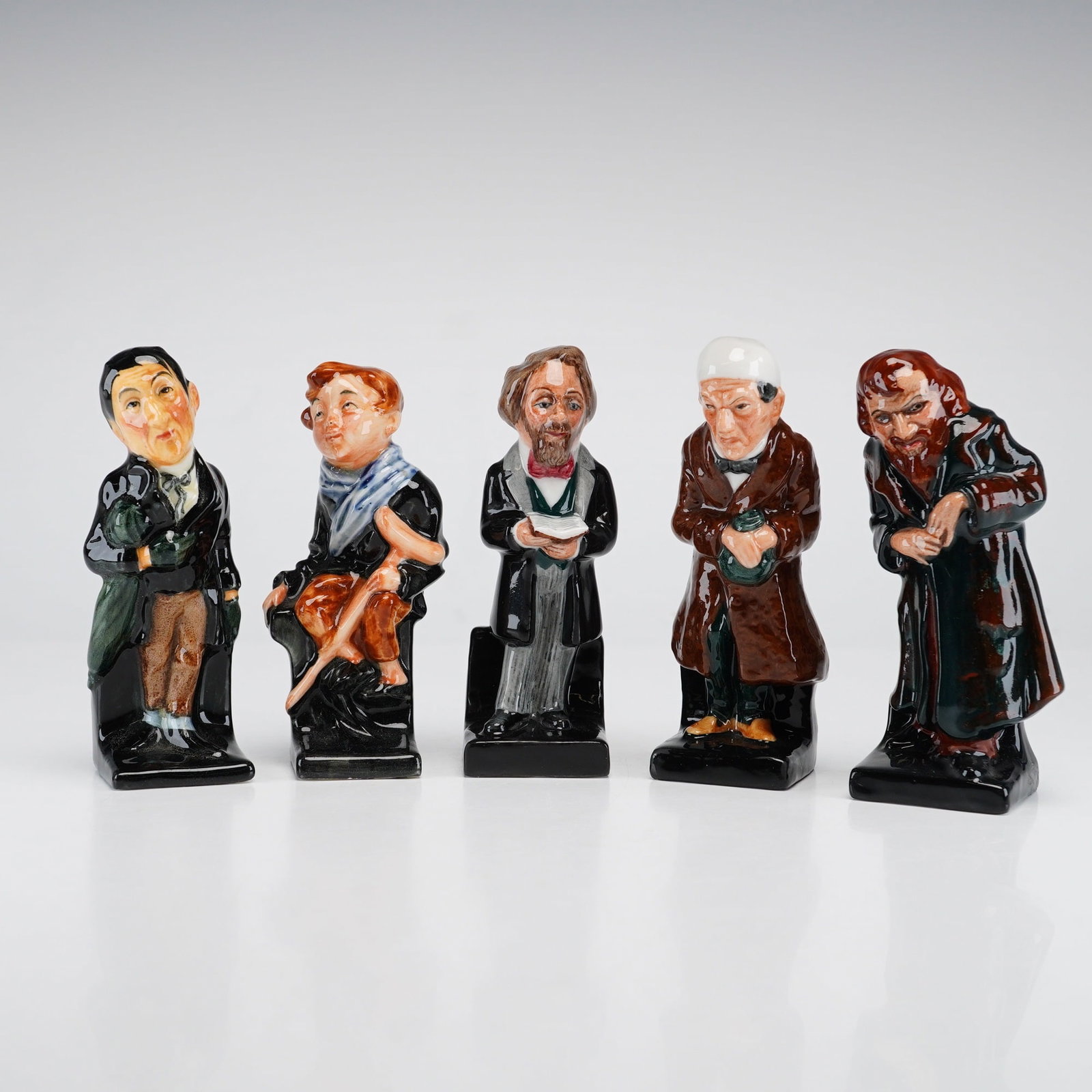 5pc Royal Doulton Glazed Ceramic Charles Dickens Miniature Figurines: This set of 5pc miniature figurines by Royal Doulton features four characters from the novels of Charles Dickens alongside a commemorative figure of the author himself. The collection includes Stiggin