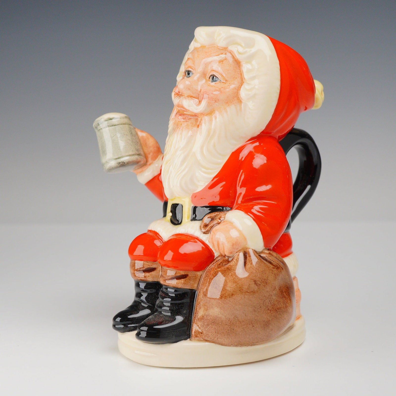 Royal Doulton Father Christmas Limited Edition Toby Jug D6940: A Royal Doulton full-figure toby jug titled Father Christmas, model number D6940. This ceramic piece is modeled in the form of Santa Claus seated on a brick-textured chimney, holding a frothing tankar