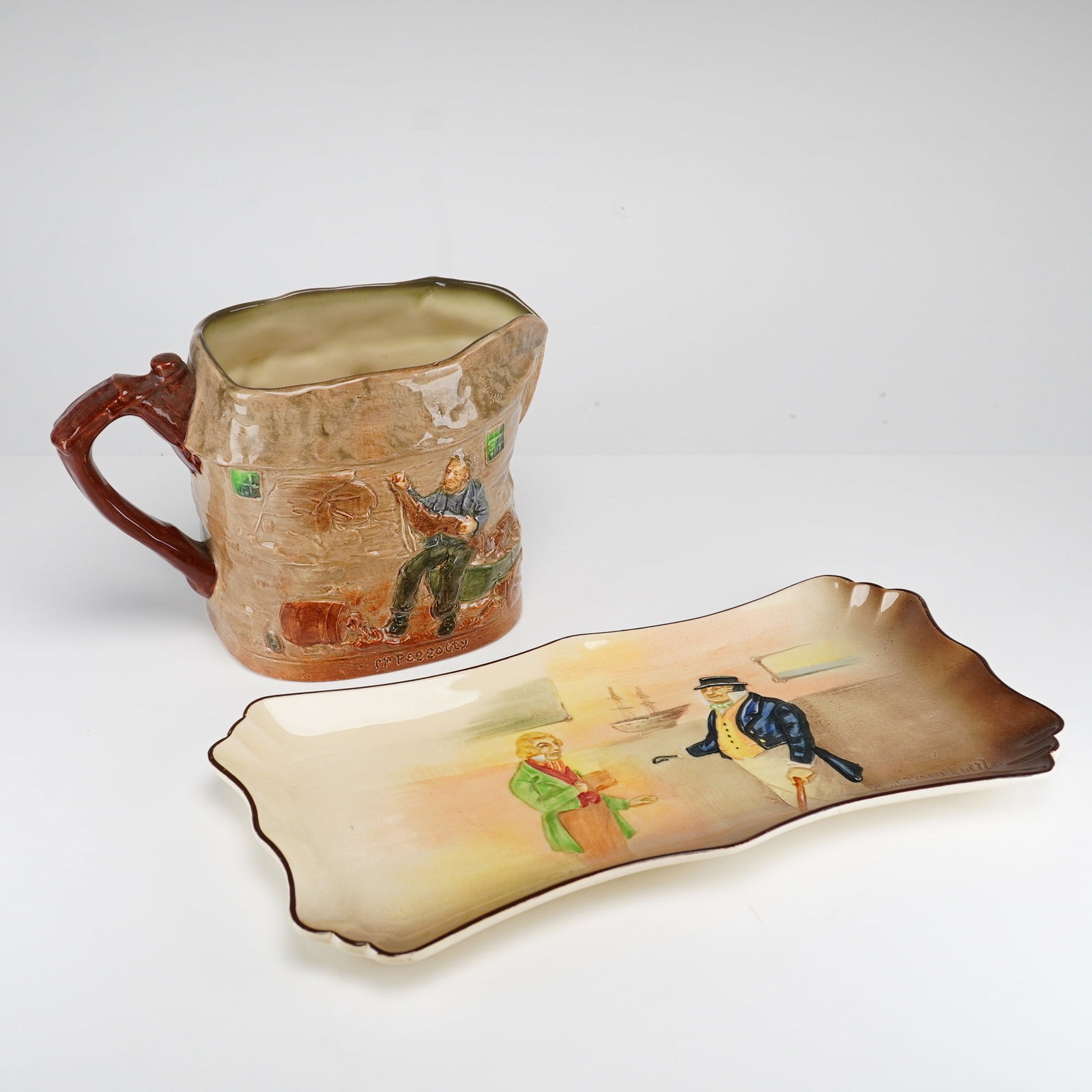 2pc Royal Doulton Dickensware Peggotty Pitcher and Mr. Toots & Captain Cuttle Platter: This lot features two pieces of Royal Doulton glazed earthenware from the Dickens Series. The first item is a relief-molded pitcher titled Peggotty, showcasing scenes from David Copperfield. The body 