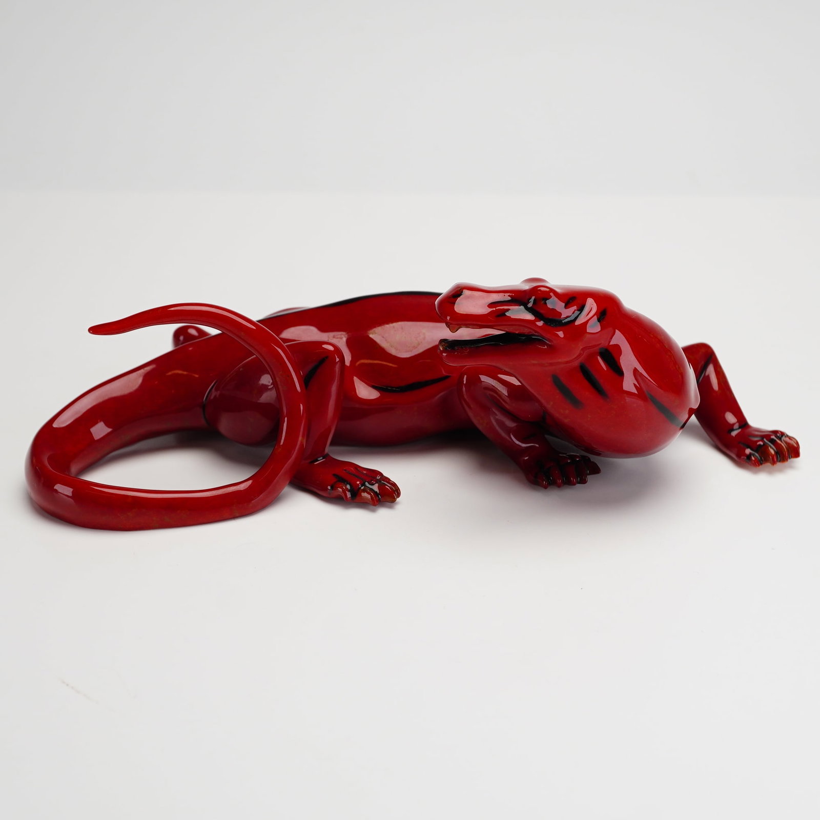 Royal Doulton Prestige Burslem Artwares Figurine, Fu Wei Dragon BA65: A flambe fired red glaze over a slender, elongated body and tail. Positioned in a resting stance on four limbs, the figurine incorporates black outlines to define the anatomical curves and physical co