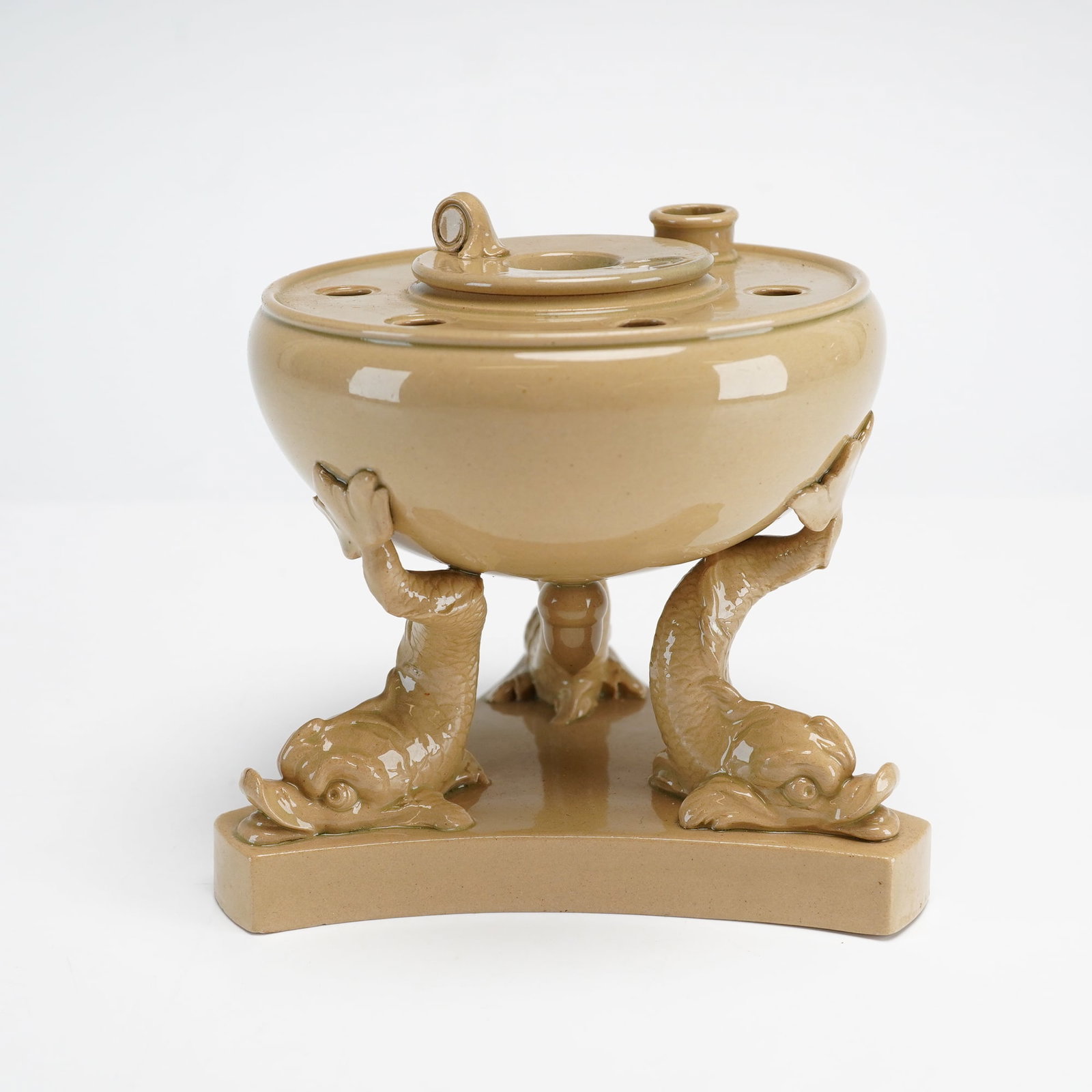 Wedgwood Glazed Dolphin Pastille Burner: Wedgwood drabware ceramic pastille burner featuring a globular bowl supported by three stylized dolphins. The vessel rests on a concave triangular tripod base. The piece is finished in a matte olive-g