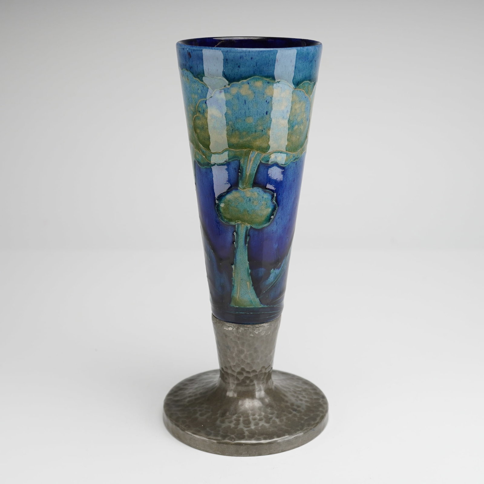 Moorcroft Pottery and Tudric Pewter Mounted Vase, Moonlit Blue: William Moorcroft floral vases decorated in the Moonlit Blue pattern, each fitted with Tudric pewter mounts. The bodies are decorated with characteristic tubelined floral motifs set against the deep, 