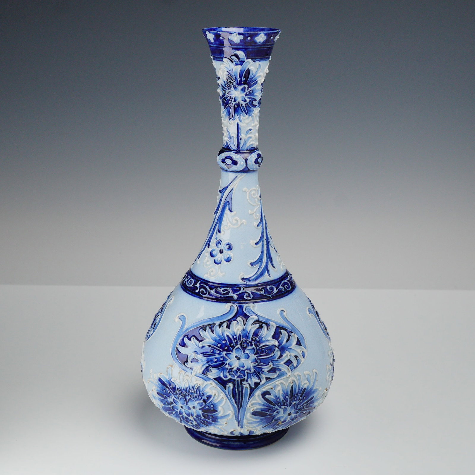 William Moorcroft Florian Ware Bottle Vase, Cornflower: Florian ware bottle vase in the 'Cornflower' pattern, decorated on a blue ground. With green signature and printed marks to the underside. Dimensions: 5.5"W x 11.25"H Weight: 1 lb. 7.1 oz.