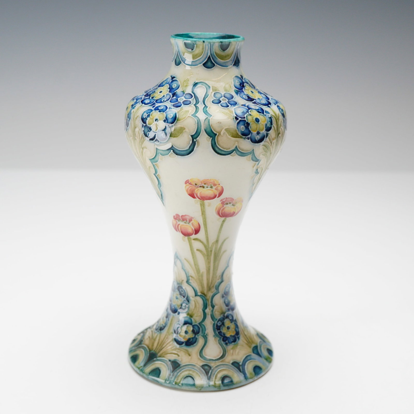 William Moorcroft for James Macintyre and Co. Florian Ware Vase with Poppies and Forget-Me-Nots: This earthenware vase is an example of Florian Ware designed by William Moorcroft for James Macintyre and Co. The small flower vase features a slender, waisted form with a bulbous shoulder and a flare