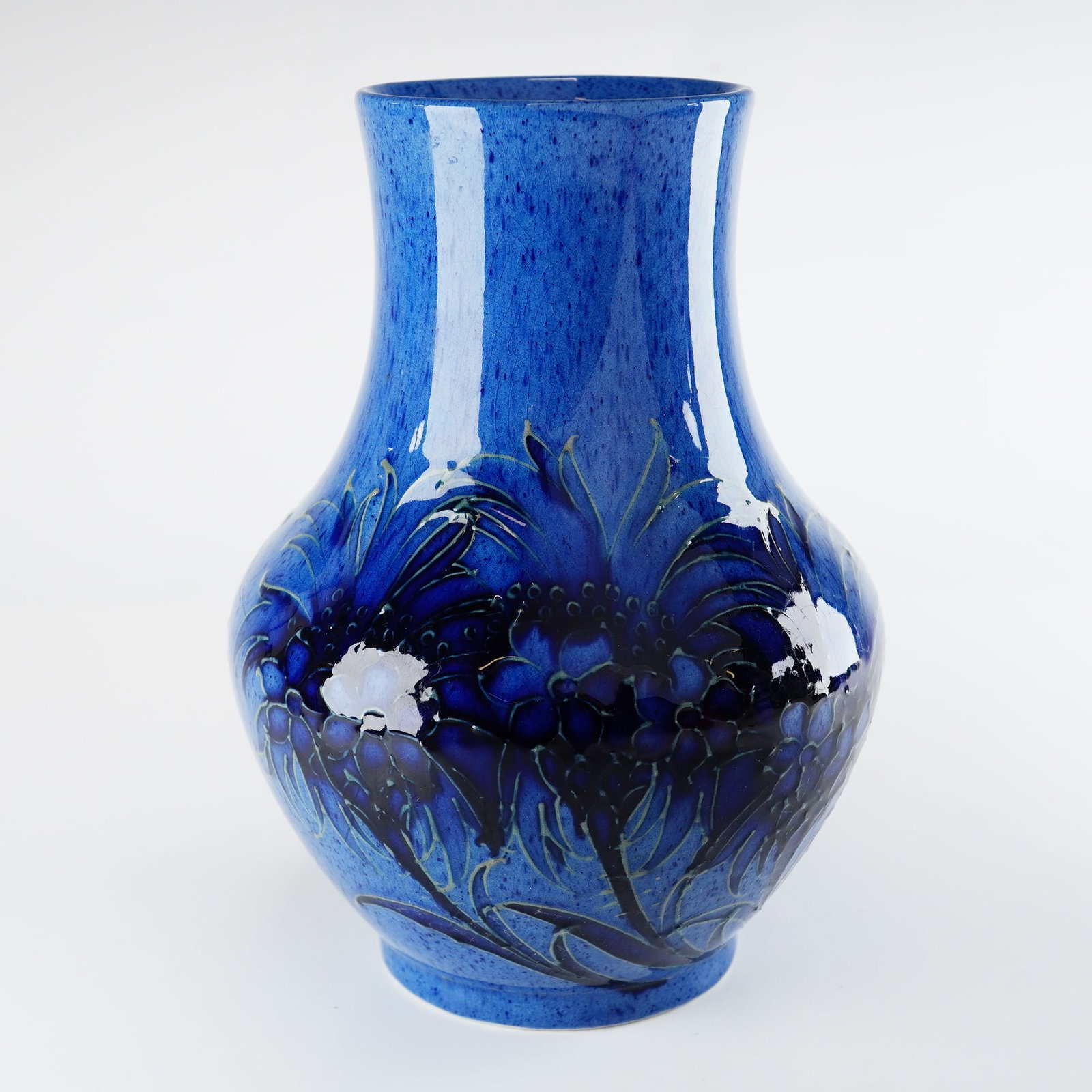 Moorcroft Pottery Powder Blue Cornflower Vase: A Moorcroft pottery vase decorated in the Cornflower pattern. This earthenware vessel features tube-lined stylized floral motifs executed in deep cobalt and navy blue tones. The design is set against 