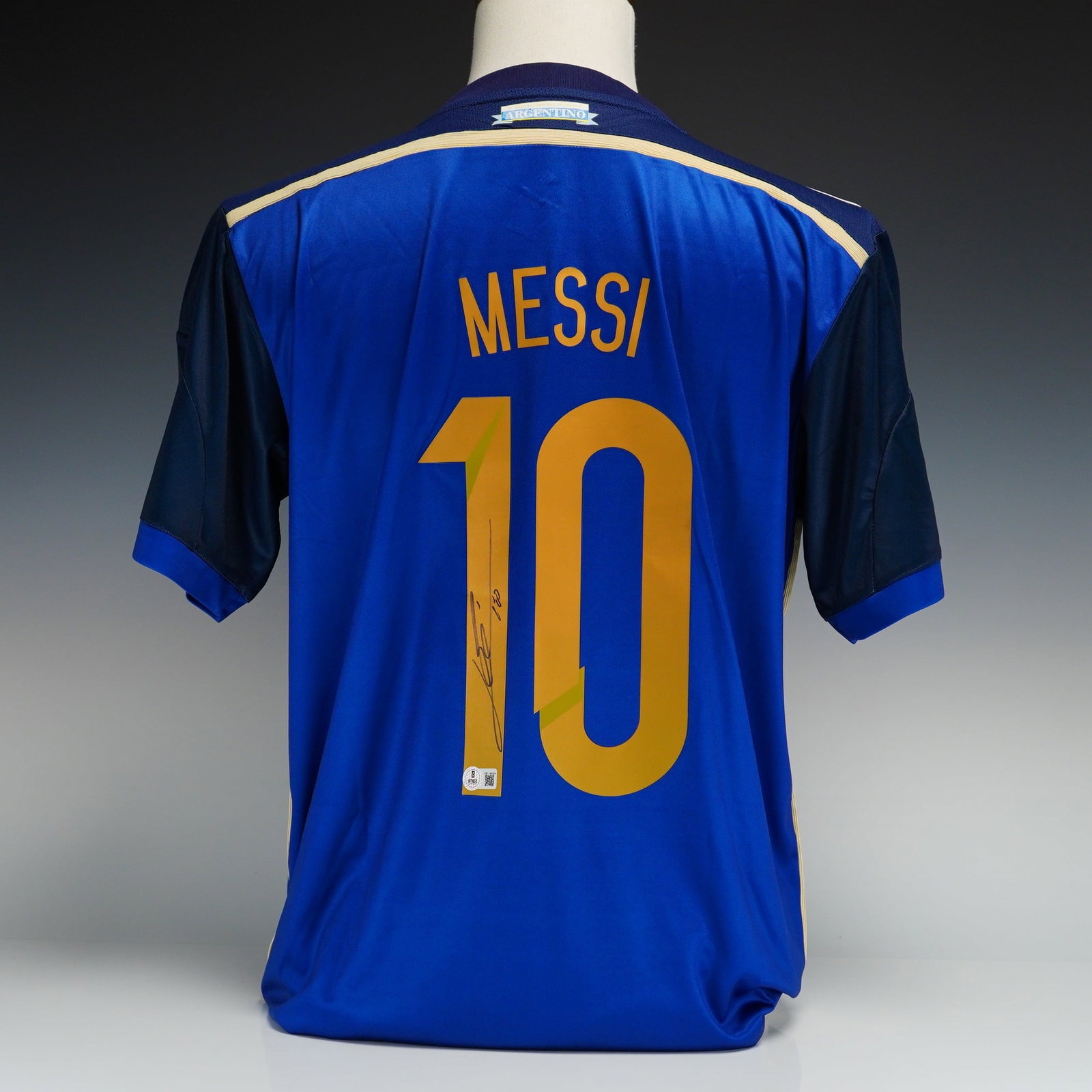 Autographed Lionel Messi Argentina 2016 Copa America Centenario Away Jersey with Beckett Witnessed: This is an autographed Argentina national team soccer jersey, specifically the away kit produced by Adidas for the 2016 Copa America Centenario. The jersey features a navy blue upper section with a ho