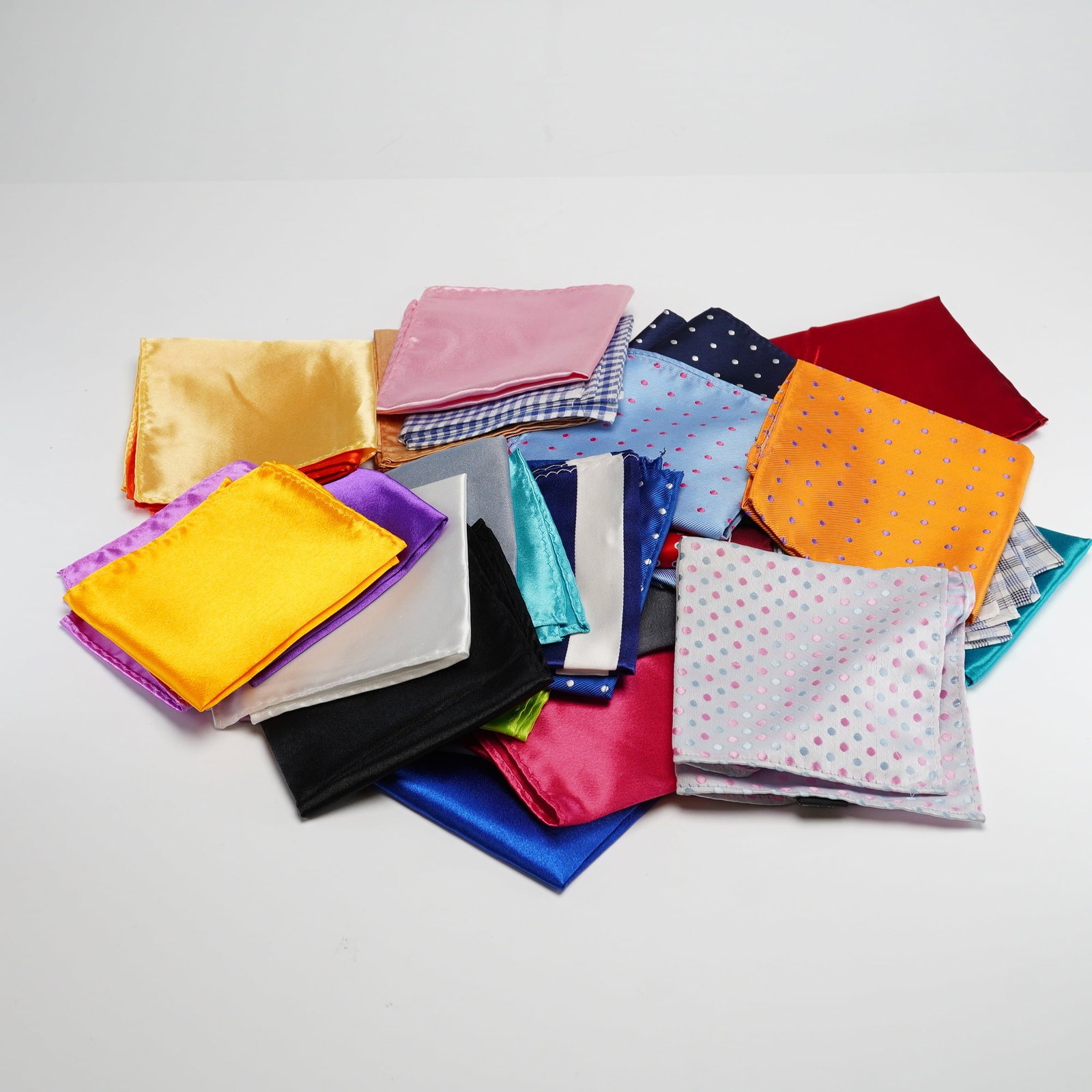 43pc Assorted Men's Silk and Satin Pocket Squares: This lot of pocket squares includes a diverse array of colors and patterns in various fabrications. The collection features items made from 100% silk and satin-finished synthetic materials. The assort