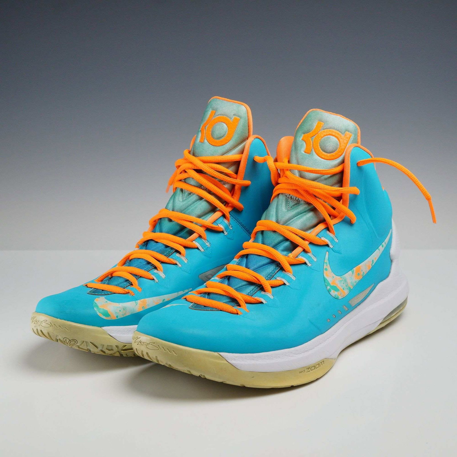 A Pair of Nike KD 5 Easter Basketball Sneakers Size 12: A pair of Nike KD V basketball sneakers in the Easter colorway, identified by style code 554988-402. The design features a turquoise blue synthetic Hyperfuse upper with contrasting total orange accent