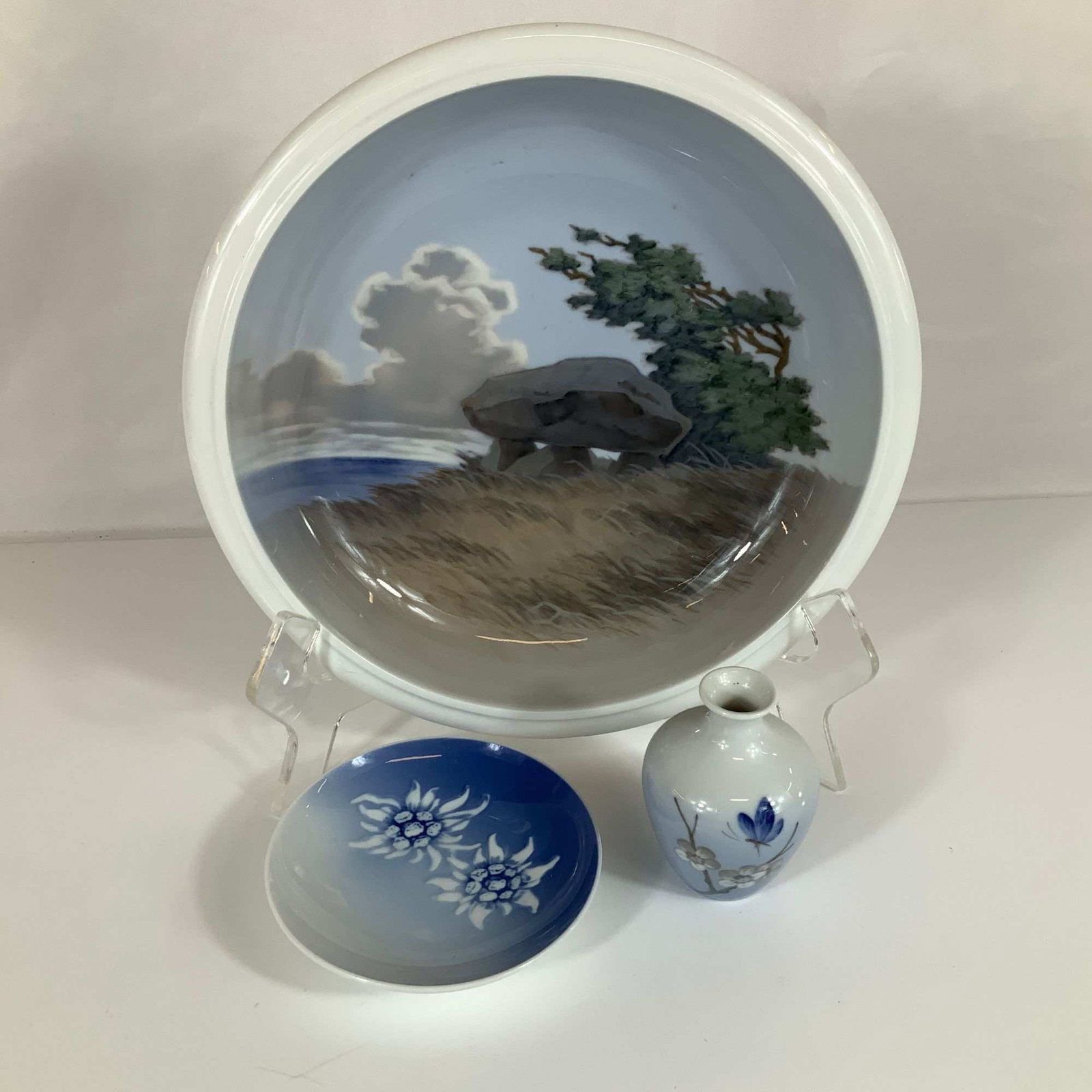 3pc Bing and Grondahl & Royal Copenhagen Bowl, Bud Vase and Small Dish: A charming three-piece lot of traditional Danish porcelain featuring iconic underglaze hand-painted designs: Royal Copenhagen Art Nouveau Landscape Bowl: A large round bowl showcasing a serene, windsw