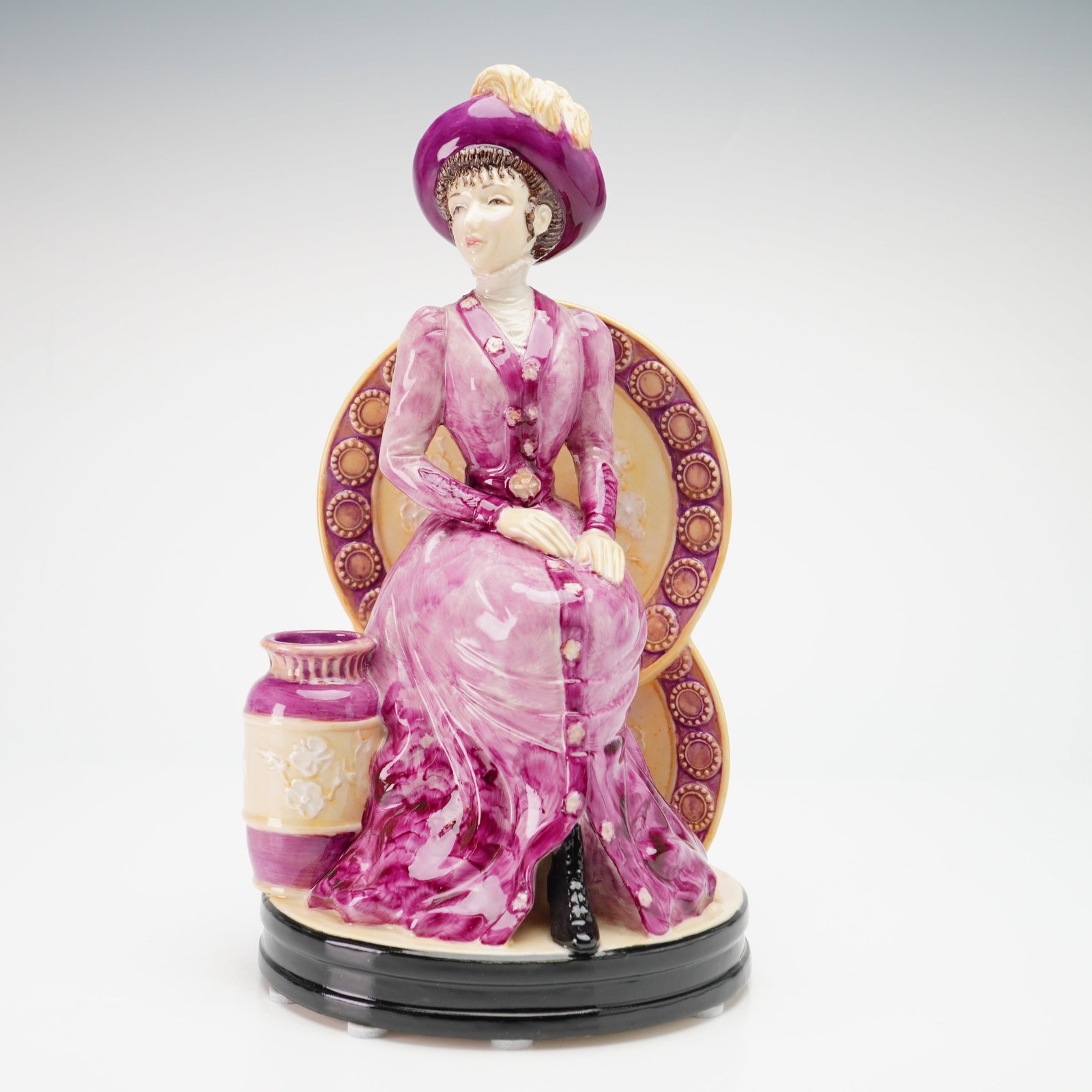 Kevin Francis Ceramics by John Michael Artist Original Proof Figurine: Sculpted by John Michael, the piece depicts a seated woman dressed in late Victorian-style attire. The figure wears a vibrant plum-colored gown with hand-painted button accents and a matching wide-bri