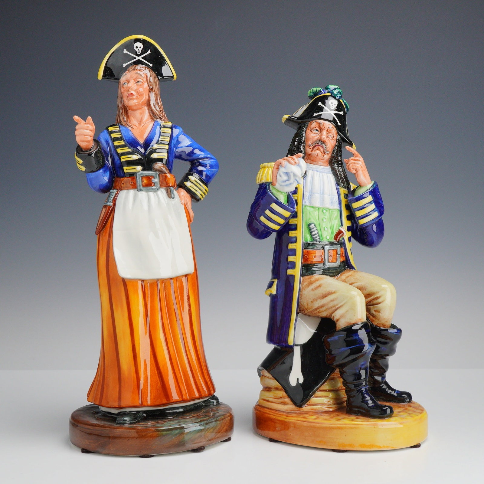 2pc Royal Doulton Porcelain Figurines, Ruth the Pirate Maid and The Pirate King: A group of polychrome glazed porcelain figurines manufactured by Royal Doulton, depicting characters from the Gilbert and Sullivan comic opera, The Pirates of Penzance. The set includes one standing f