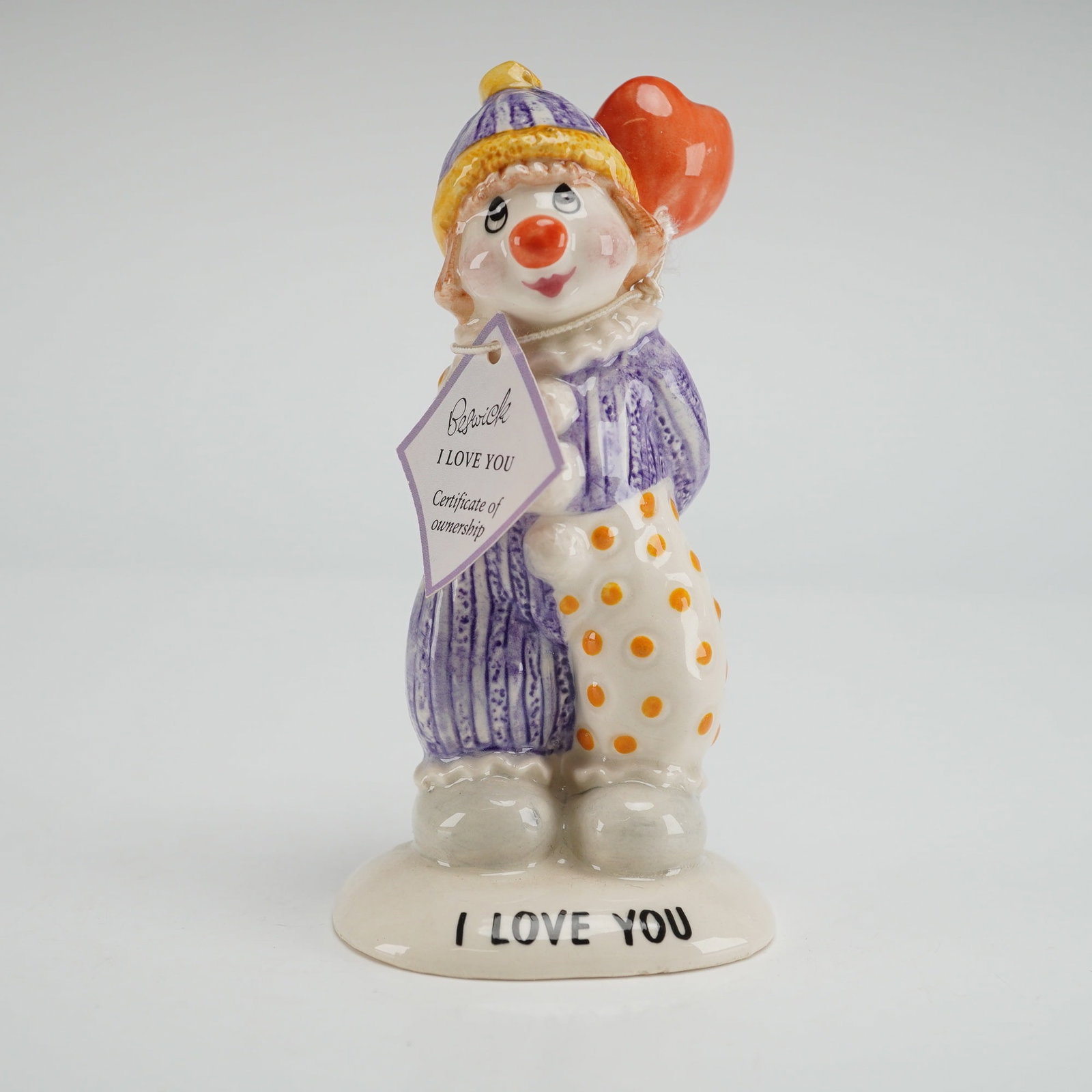 John Beswick Ceramic Clown Figurine I Love You: The piece features a whimsical clown in a tender pose, conveying a warm sentimental theme that is characteristic of Beswicks distinctive style. Finished in a smooth glazed surface with carefully appli