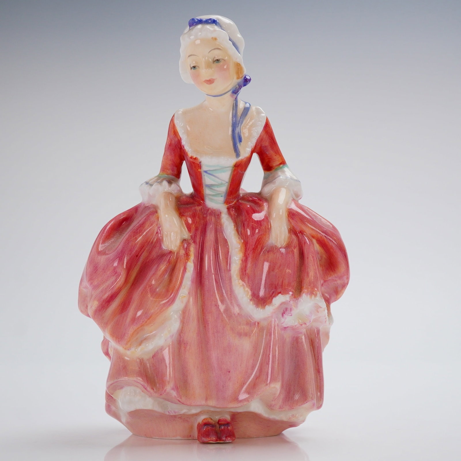 Royal Doulton Figurine, Goody Two Shoes HN2037: A Royal Doulton Figurine, titled 'Goody Two Shoes' (Model HN2037), crafted from glazed bone china. The figure depicts a young woman dressed in 18th-century style, characterized by a wide, panniered sk