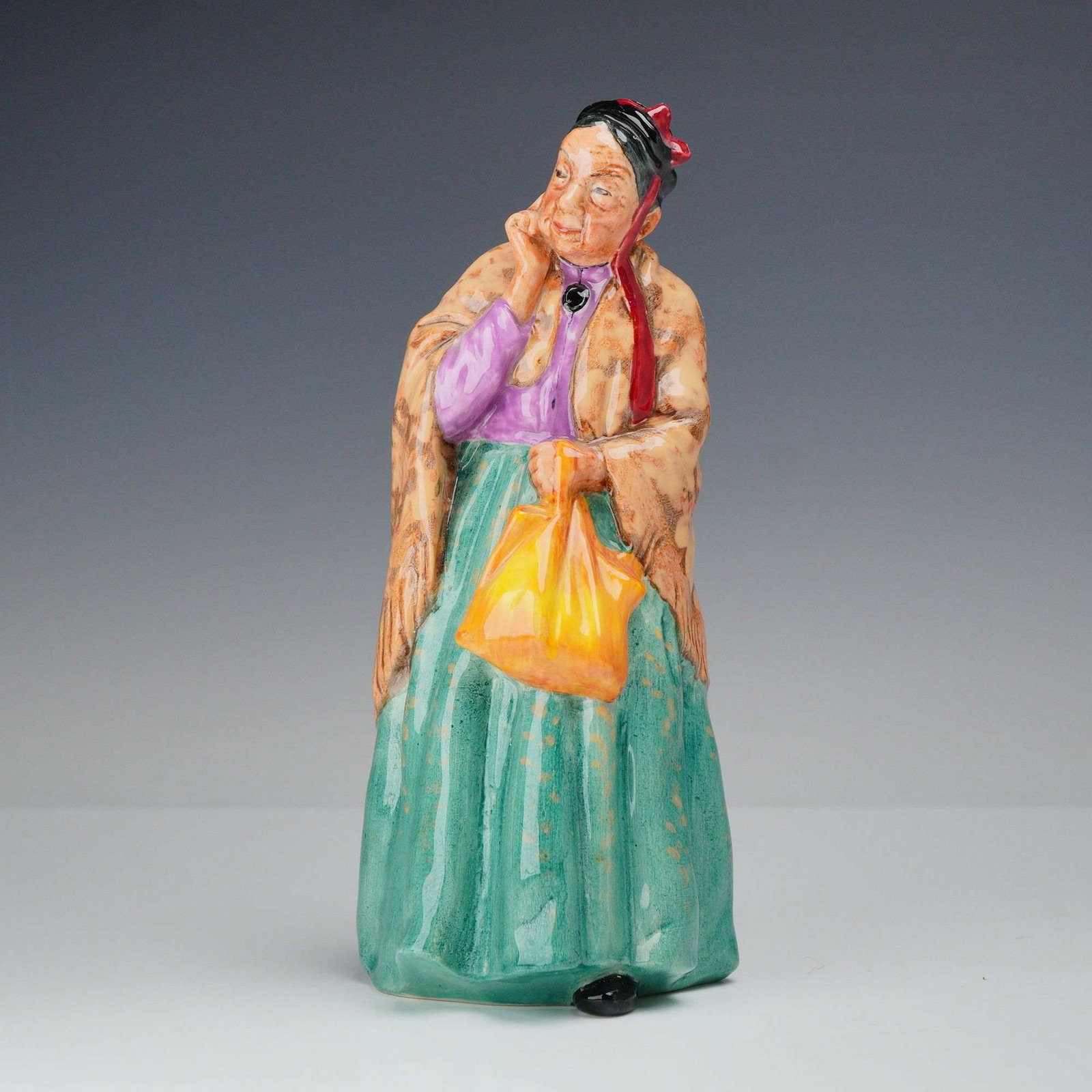 Royal Doulton Porcelain Figurine Bridget HN 2070: A Royal Doulton glazed porcelain figurine titled Bridget, model number HN 2070, designed by Leslie Harradine as part of the Harradine Classics series. The figure depicts Bridget with her shawl and han