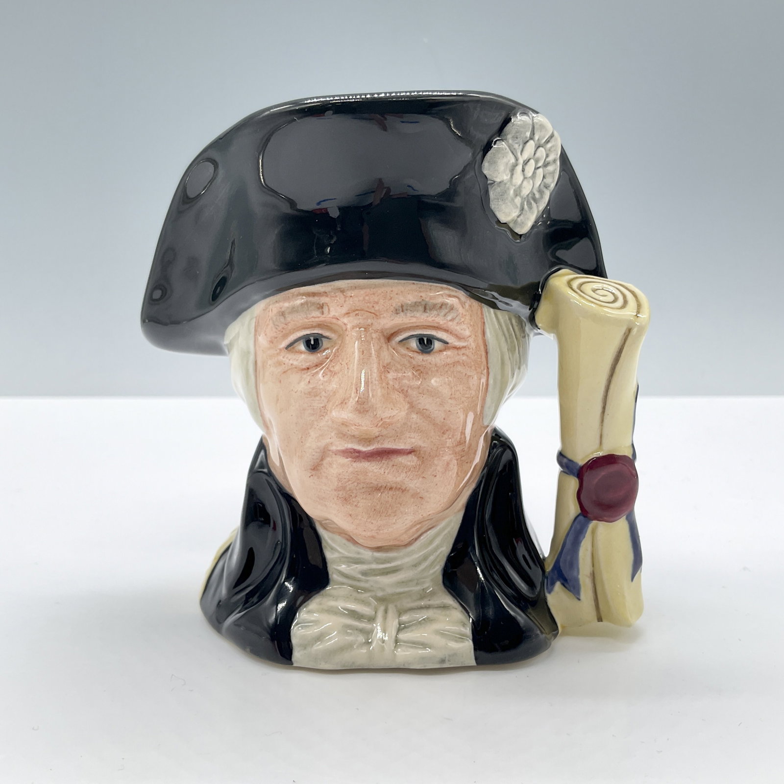 George Washington D6824 Small Royal Doulton Character Jug: Style One, Declaration of Independence handle. Black hat and coat; beige shirt. Royal Doulton backstamp. Artist: Stanley J. Taylor Dimensions: 4"H Date or Era: 1989 - 1991 Manufacturer or Brand: Royal