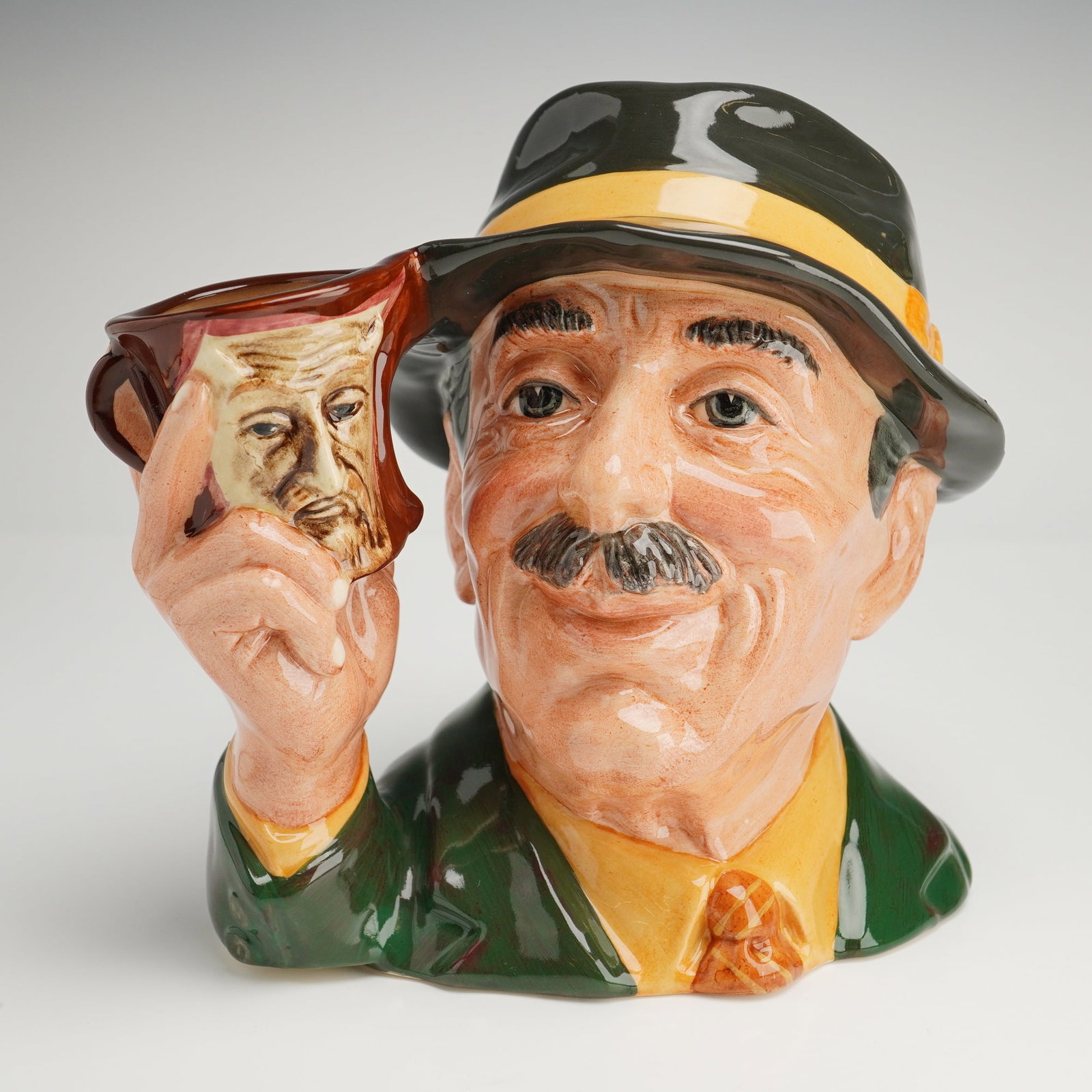 Royal Doulton Character Jug D6796 The Collector: A Royal Doulton glazed ceramic character jug D6796 titled The Collector, part of The Collecting World series produced for Kevin Francis Ceramics. This hand-made and hand-painted piece depicts a smilin