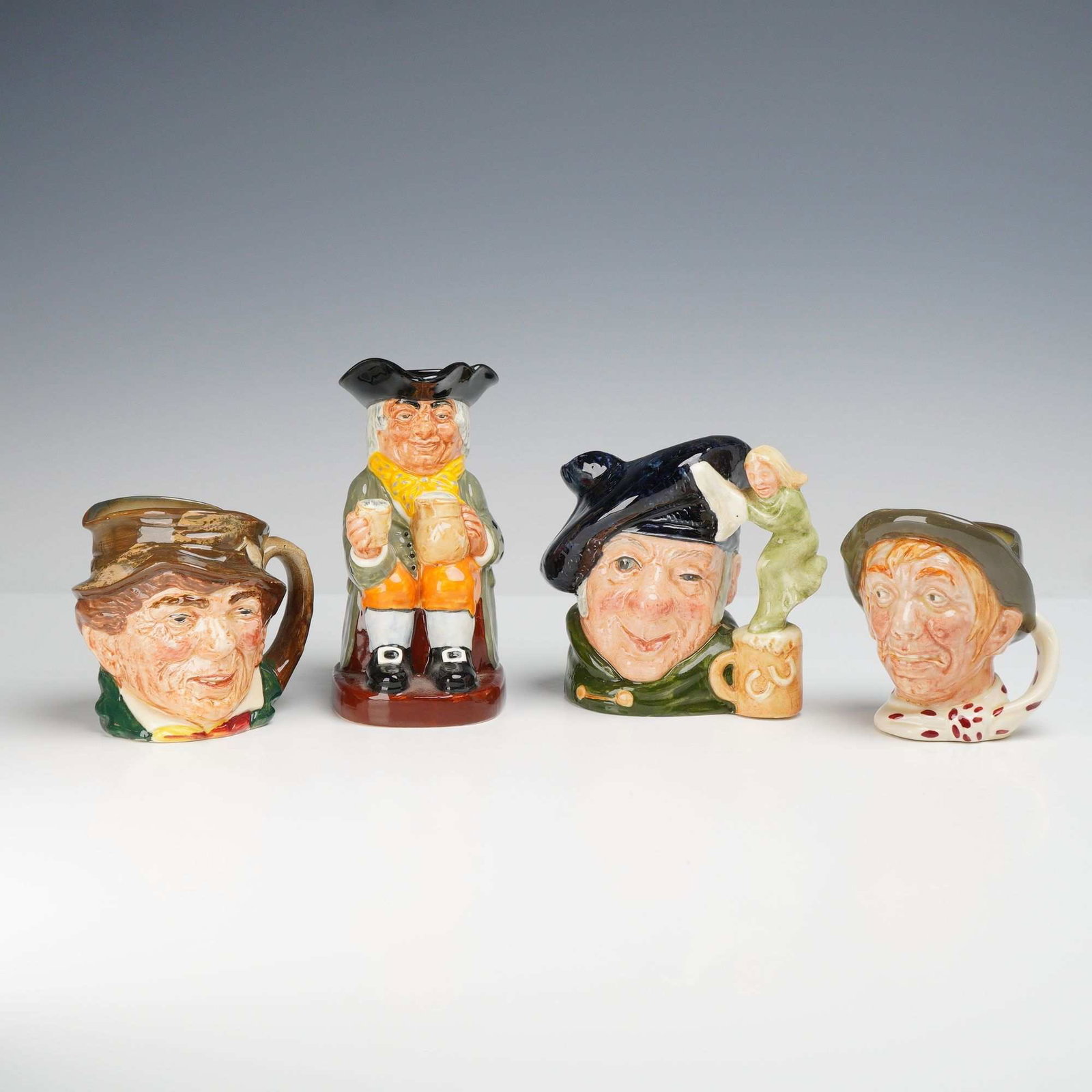 Collection of Four Royal Doulton Character and Toby Jugs Including Tam o'Shanter, Paddy, Jarge, and: This is a collection of four Royal Doulton hand-painted glazed earthenware jugs, consisting of three character jugs and one full-bodied Toby jug. The selection includes the Paddy character jug, portra