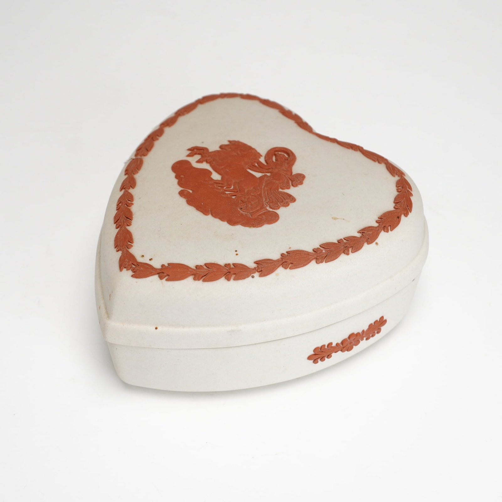 Wedgwood Jasperware Terracotta on White Heart-Shaped Trinket Box: This heart-shaped lidded trinket box is produced by Wedgwood in England. It is crafted from unglazed matte stoneware known as jasperware, featuring a terracotta-on-white color scheme. The lid is decor
