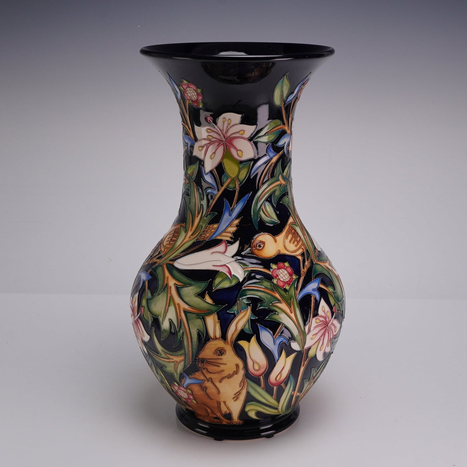 Moorcroft Pottery by Nicola Slaney Vase, The Woodland Road Pattern: This earthenware art pottery piece is of baluster form, featuring a globular body that tapers to a slender neck and terminates in a flared trumpet-style rim, all supported by an integrated circular fo