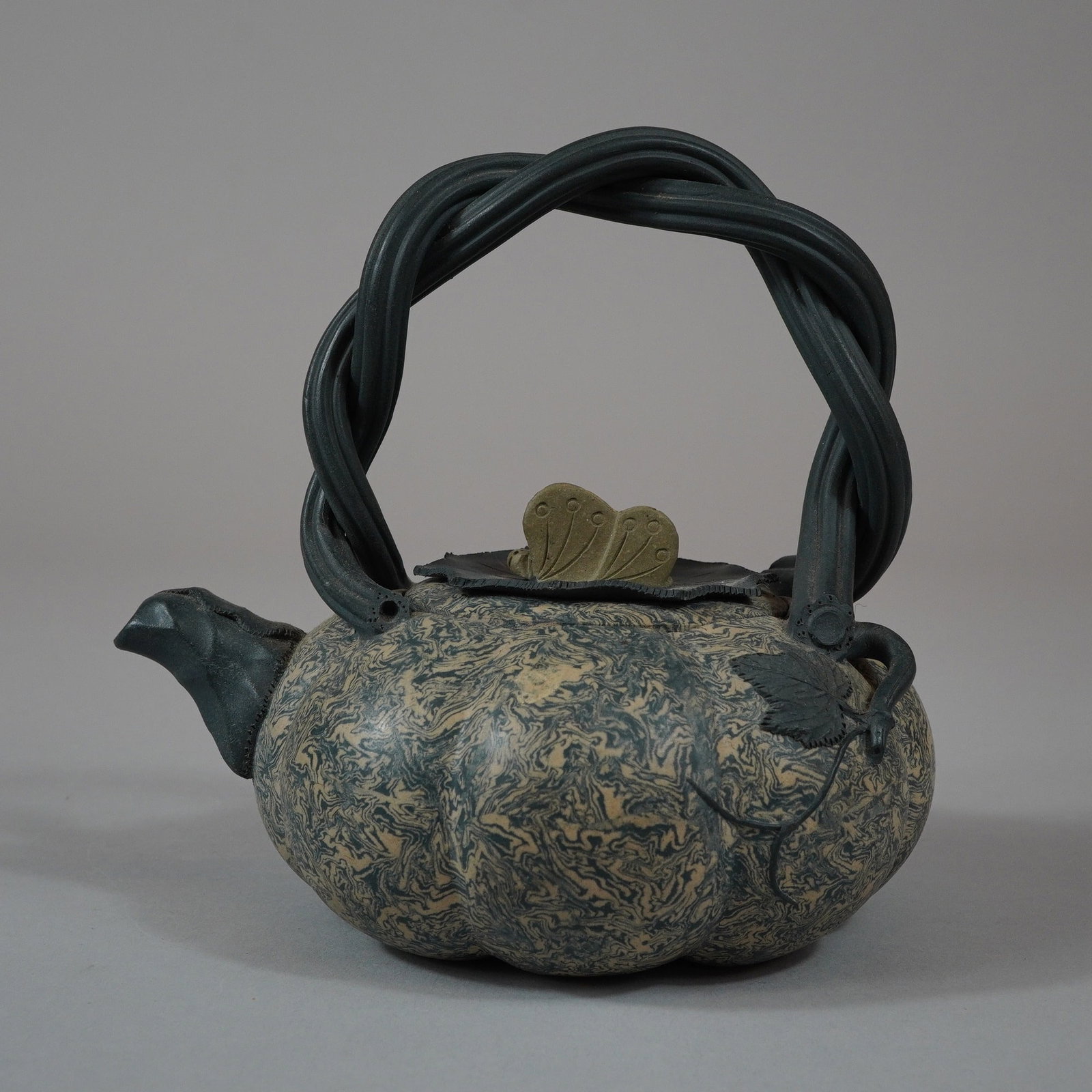 Chinese Yixing Zisha Pumpkin Clay Teapot: A Chinese stoneware teapot featuring a lobed, globular body executed in a marbled style using contrasting blue-grey and buff-colored clays. The vessel is designed with an overhead bridge handle fashio
