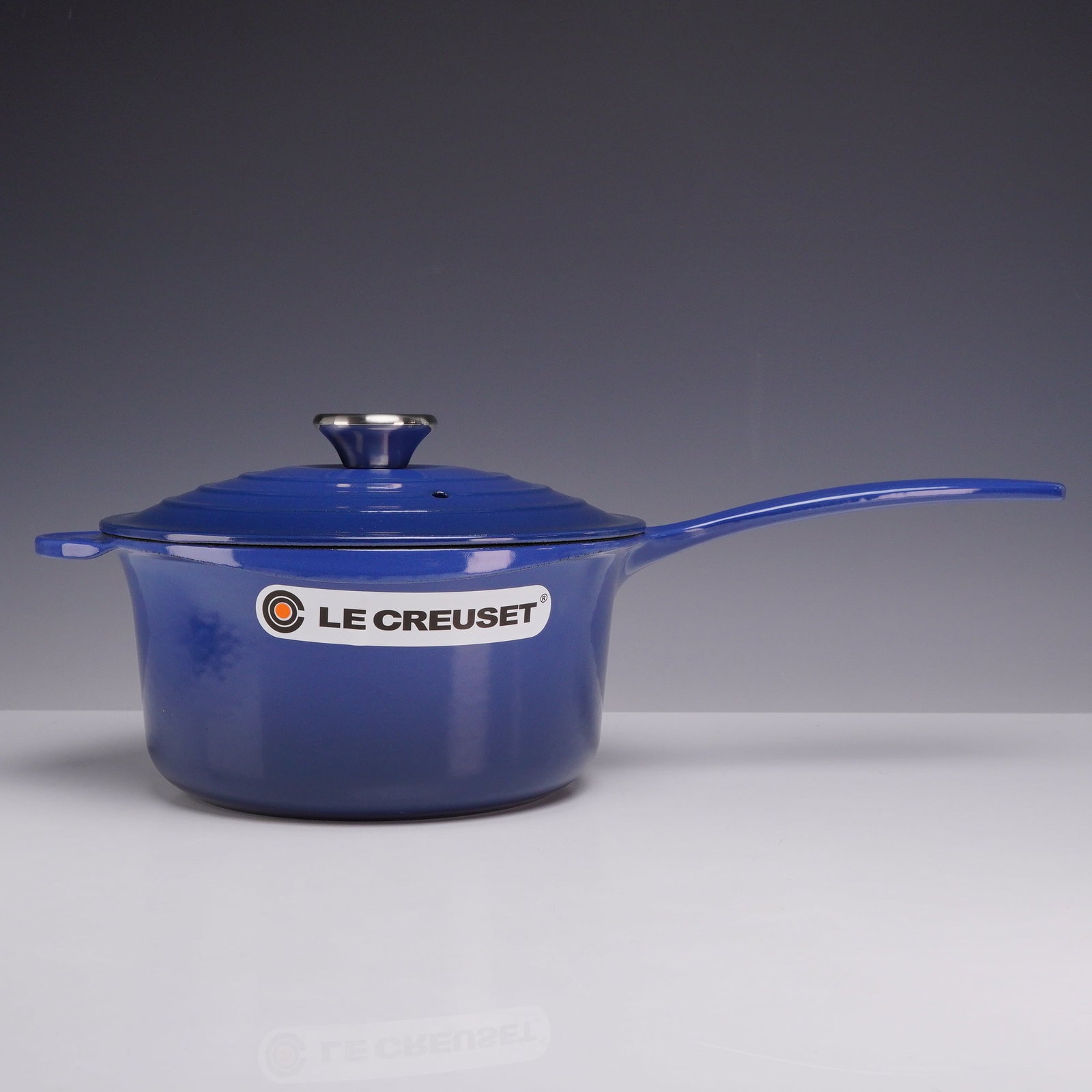 Le Creuset Cobalt Blue Enameled Cast Iron 2.25 Quart Saucepan with Lid: This lot features a Le Creuset Signature saucepan crafted from heavy-duty enameled cast iron. The exterior is finished in a deep cobalt blue enamel, contrasting with a smooth, cream-colored enamel int