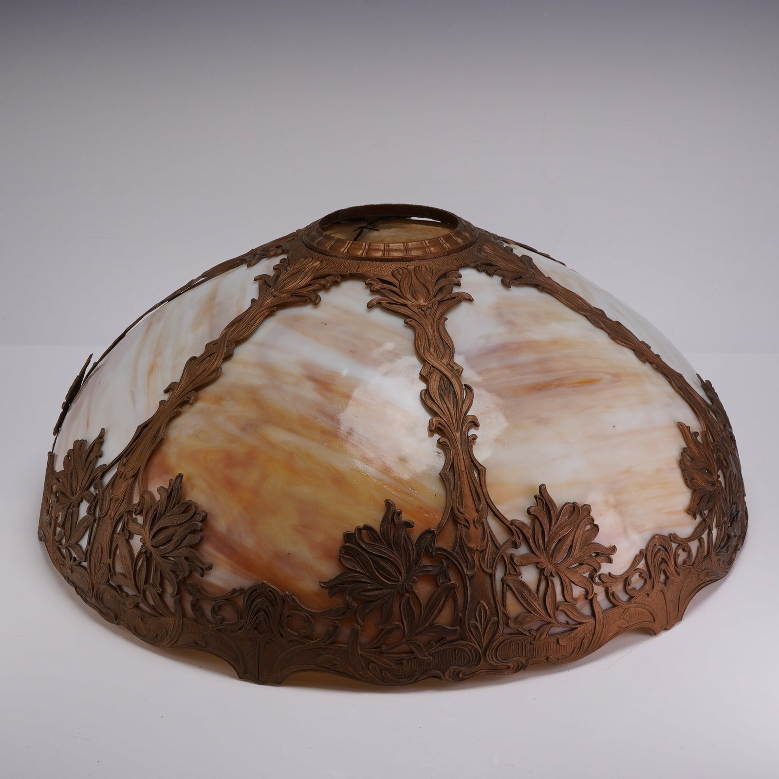 Art Nouveau Style Metal and Slag Glass Lamp Shade: An Art Nouveau style domed lamp shade featuring six curved panels of variegated caramel slag glass. The shade is constructed with a cast metal filigree overlay featuring a dark bronze-toned patina.