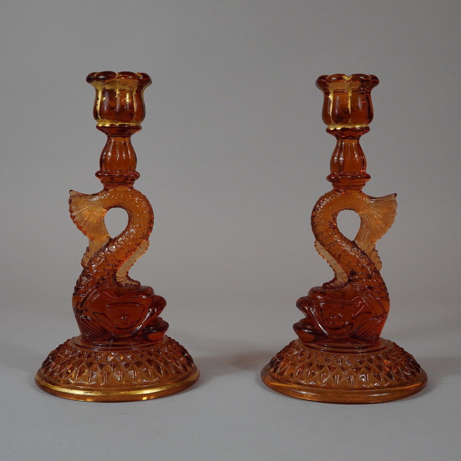 A Pair of Amber Pressed Glass Dolphin Style Candlesticks (1 of 3)