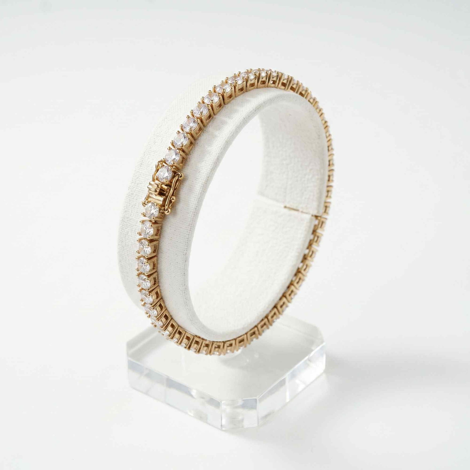 Gold Plated Sterling Silver Tennis Bracelet with Clear Rhinestones: This tennis bracelet features a continuous row of round, brilliant-cut clear rhinestones set in gold-plated sterling silver. Each faceted stone is secured within a four-prong setting. The bracelet is 