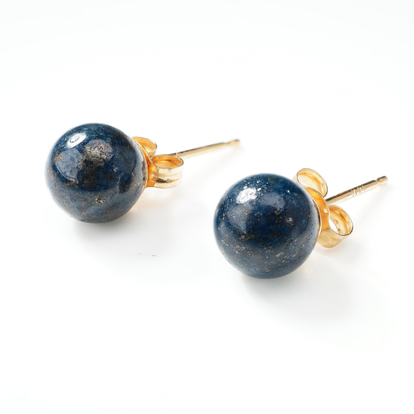 Pair of 14K Yellow Gold Lapis Stud Earrings: A matched pair of stud earrings featuring spherical lapis gemstone beads. Each polished blue gemstone is mounted on a 14-karat yellow gold post and secured with a yellow gold butterfly friction back. 