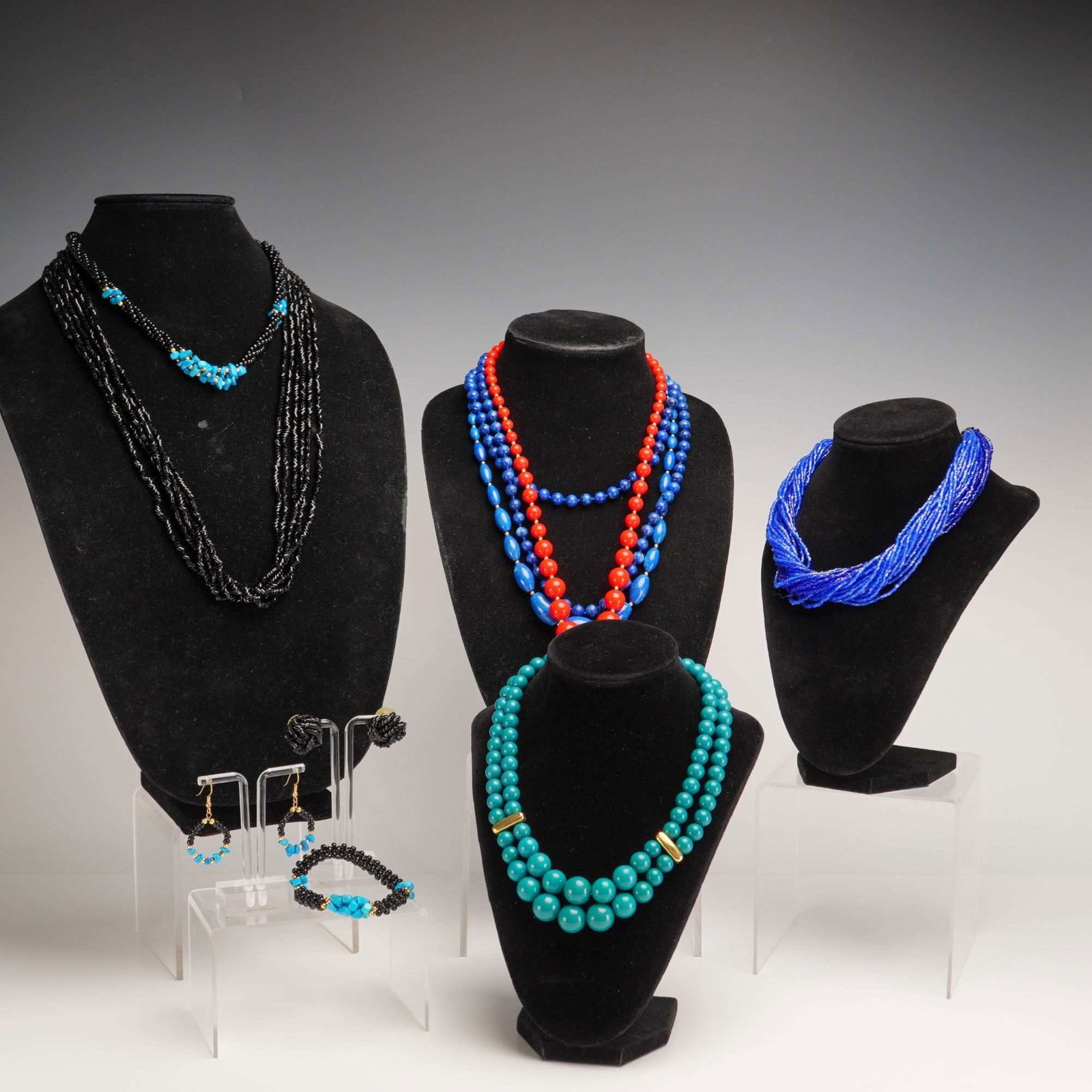8pc Costume Jewelry Necklaces and Coordinating Earrings Lot: An 8pc collection of costume jewelry necklaces and earrings featuring various colors and materials. The assortment includes a double-strand collar necklace with graduated teal-colored resin beads, gol
