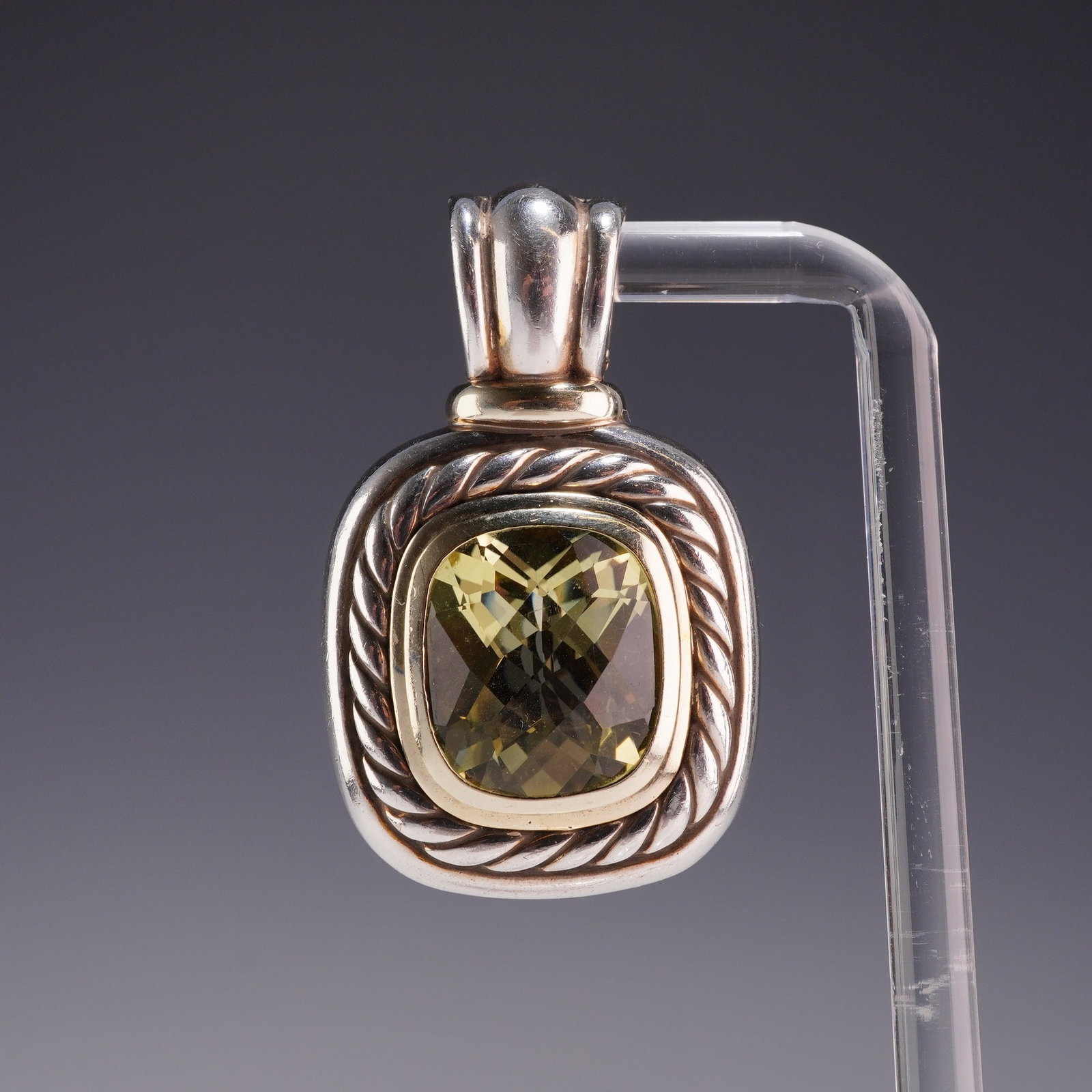 David Yurman Sterling Silver and 14K Yellow Gold Albion Prasiolite Pendant: A David Yurman sterling silver and 14k yellow gold pendant from the Albion collection. The piece features a central cushion-cut faceted Pras iolite, also known as green amethyst, of a pale yellowish-g