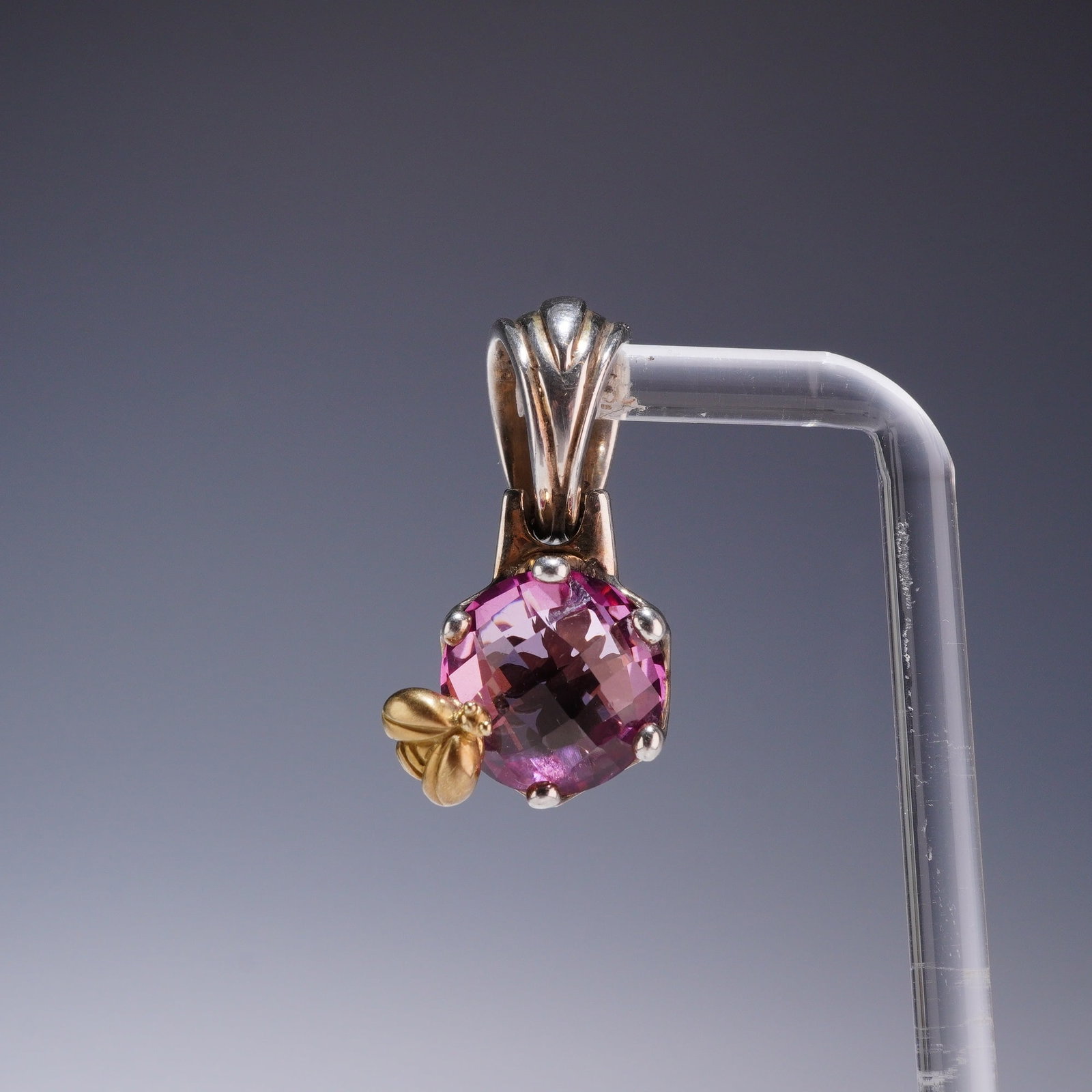 Saint Sterling Silver and 18K Gold Pink Sapphire Bee Pendant: This designer pendant is a two-tone creation by Saint, featuring a nature-inspired bee motif. The central round faceted pink sapphire is held within a four-prong sterling silver setting. A detailed