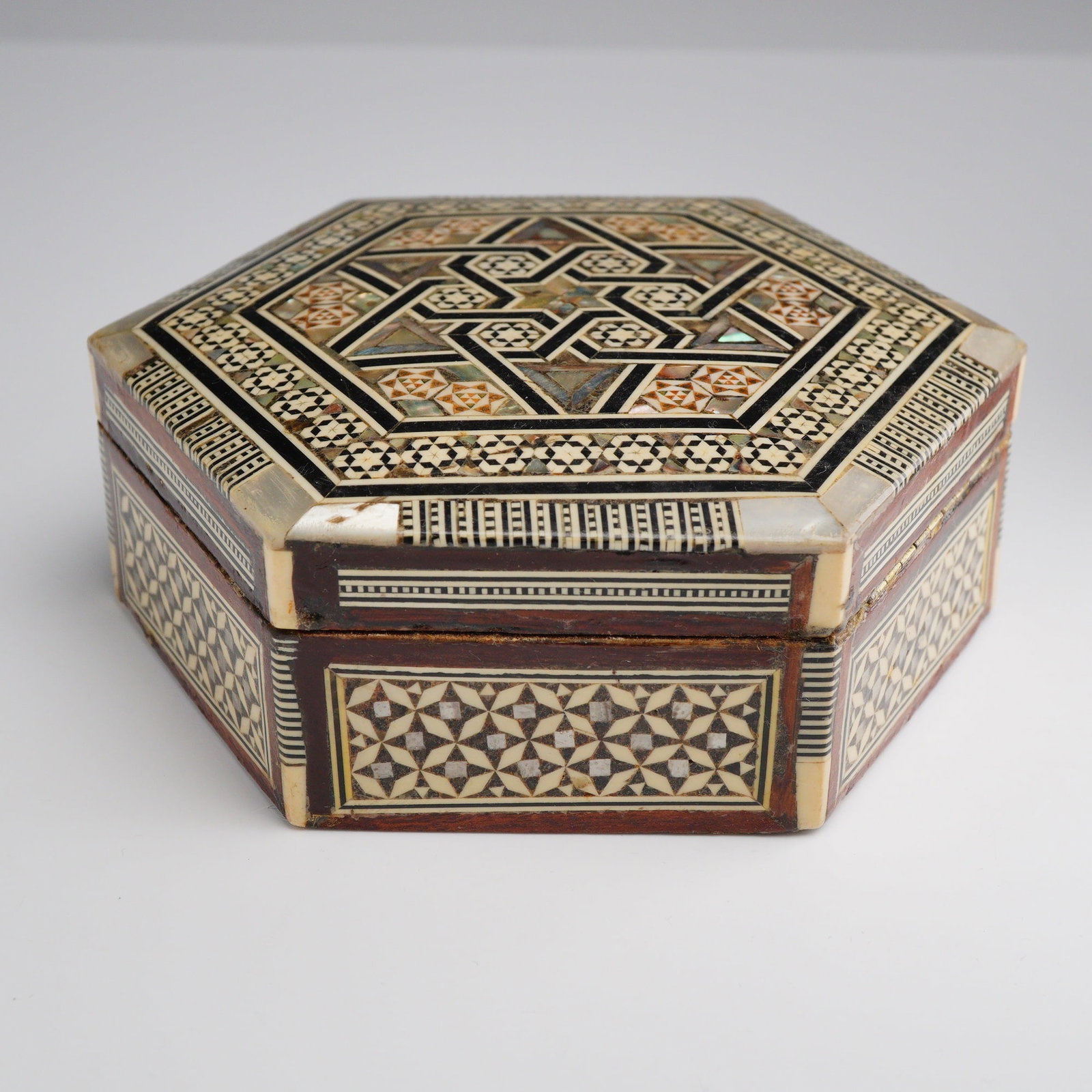 Middle Eastern Sadeli Inlaid Wooden Hexagonal Jewelry Box: This hexagonal wooden box is decorated with intricate micro-mosaic inlay known as Sadeli marquetry, a technique traditionally associated with the Levant region, particularly Damascus and Cairo. The