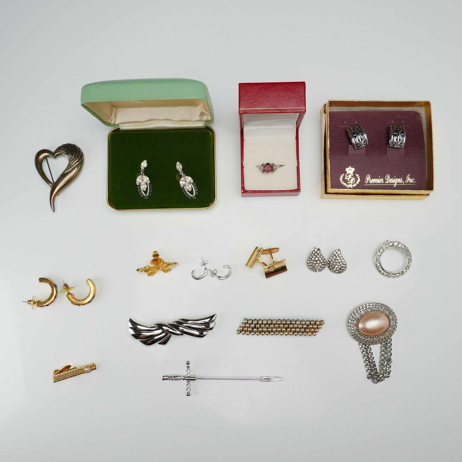 Assortment of Fifteen Costume Jewelry Pieces Featuring Premier Designs and Vintage Styles: This 15-piece custom costume jewelry collection includes 5 pairs of earrings, 5 brooches, 2 pins, 1 tie clip, 1 ring, and 1 pair of cufflinks. The lot contains a pair of silver-toned textured hoop