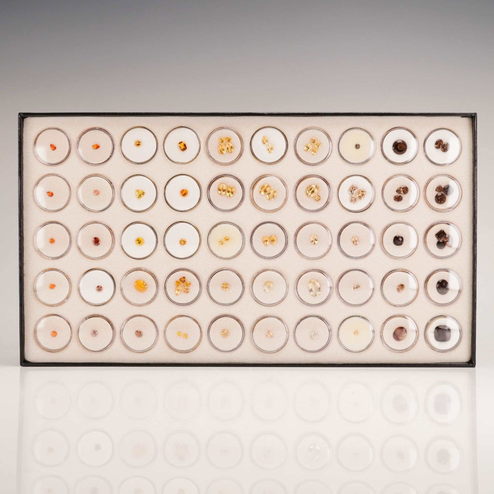 Assorted Mixed Gem Collectors Group: An assorted mixed gem collectors group comprising numerous loose faceted gemstones in a range of warm colors. The collection includes stones in shades of pale yellow, bright gold, vibrant orange, redd