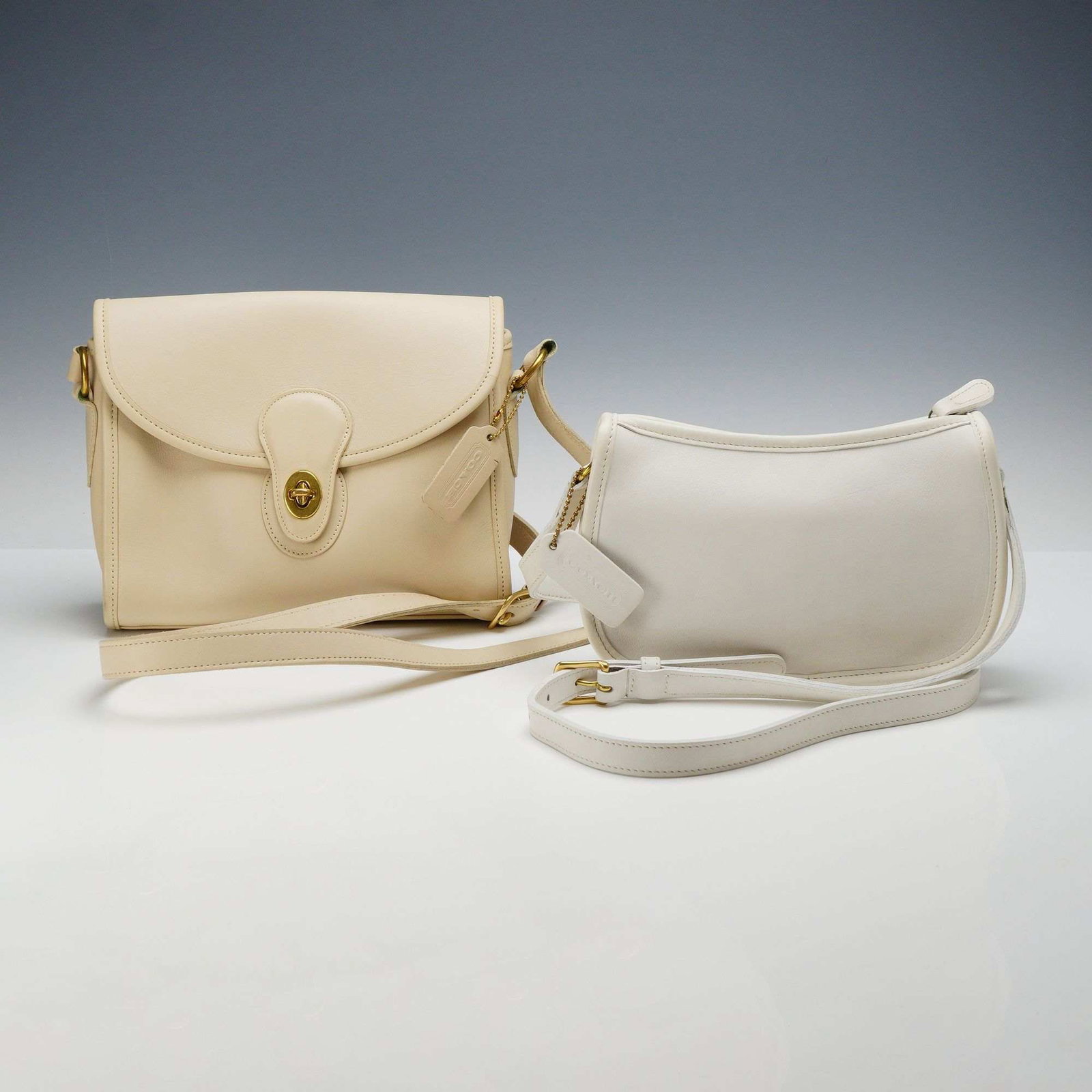 Two Vintage Coach Leather Shoulder Bags in Beige and White: This lot includes two vintage Coach shoulder bags, one beige and one white, constructed from signature glove-tanned full-grain cowhide. The first item is a crossbody flap bag in a putty beige color, f