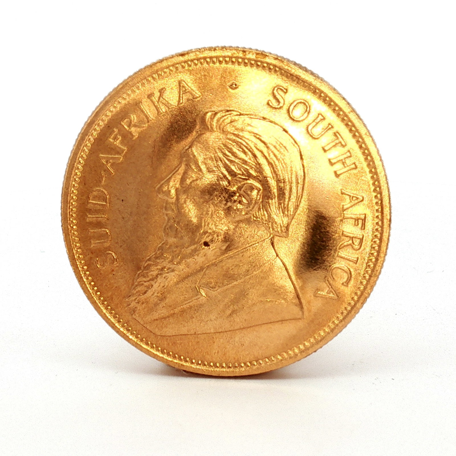 1978 South Africa Krugerrand One Ounce Gold Coin: Obverse coin is of bust Paul Kruger facing left; Reverse has Springbok walking right with date mark split; Lettering is Krugerrand with date, CLS Fyngoud 1 oz. Fine Gold. Dimensions: 32.69mm Date or E