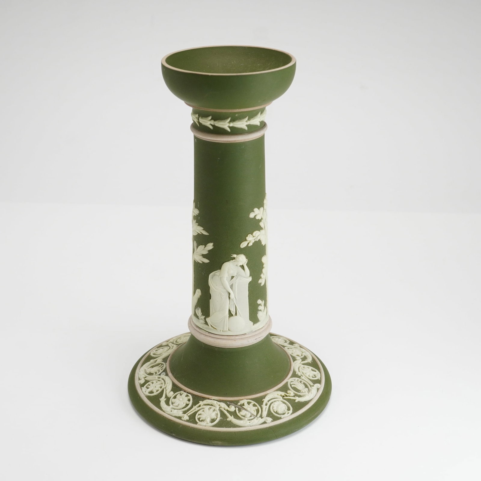 Neoclassical Sage Green Jasperware Candlestick: This columnar candlestick is crafted from sage green and white stoneware, a style known as jasperware, and is attributed to Wedgwood. The piece features a matte green ground with applied white bas-rel