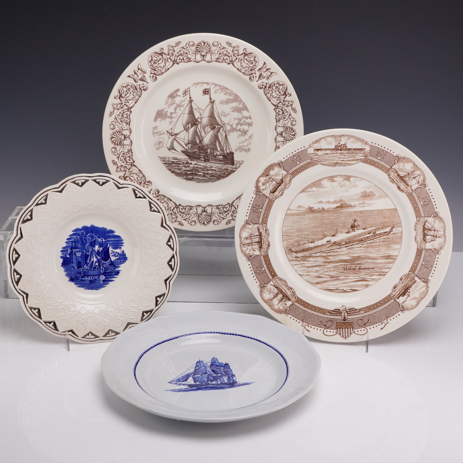 A Collection of Four Wedgwood Earthenware Maritime Commemorative Plates: A group of four English earthenware plates manufactured by Wedgwood, each featuring maritime-themed transfer-printed decoration. This collection includes a variety of historical and commemorative subj