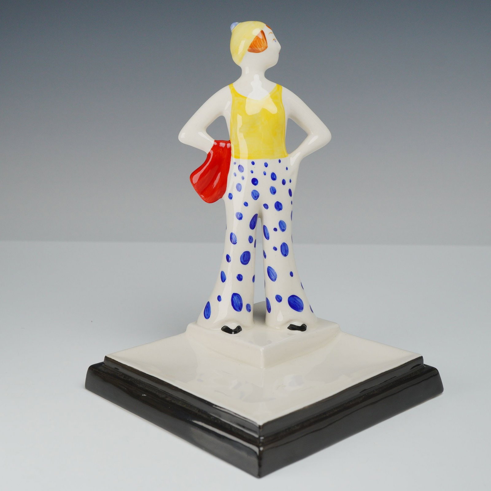 Wedgwood Clarice Cliff Collectors Club Centenary Collection Figurine: A Wedgwood Clarice Cliff Collectors Club ceramic figurine was produced in 1999 as part of the Centenary Collection. The figure is modeled in a standing pose with hands on hips, depicting a woman in Ar