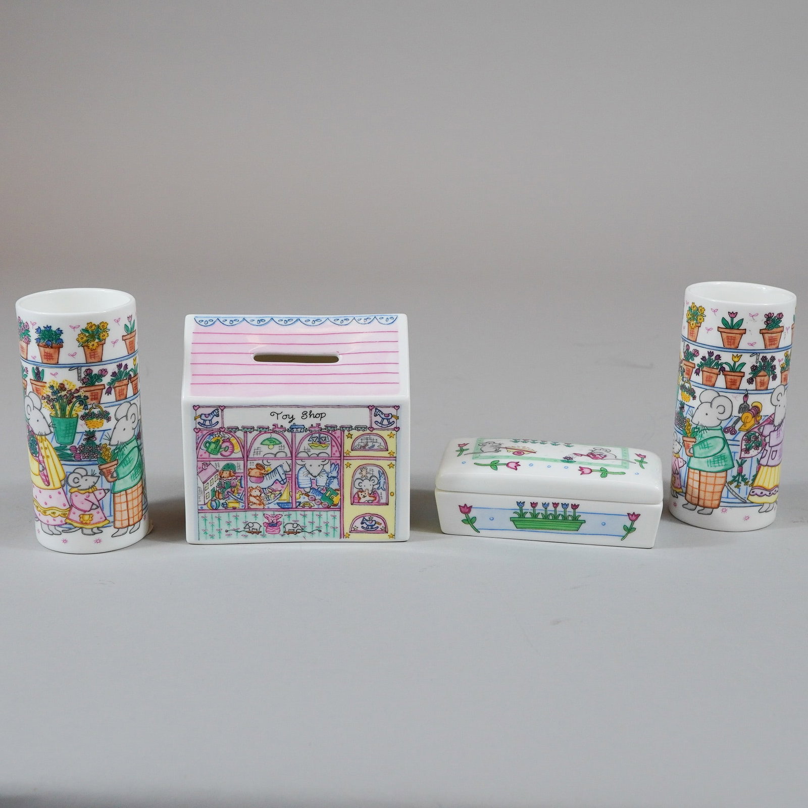 4pc Wedgwood Bone China Nursery Ware by Michelle Cartlidge: This 4-piece set of Wedgwood bone china nursery ware features illustrations by Michelle Cartlidge, dated 1988. The collection includes a house-shaped money box titled Toy Shop, a rectangular lidded tr
