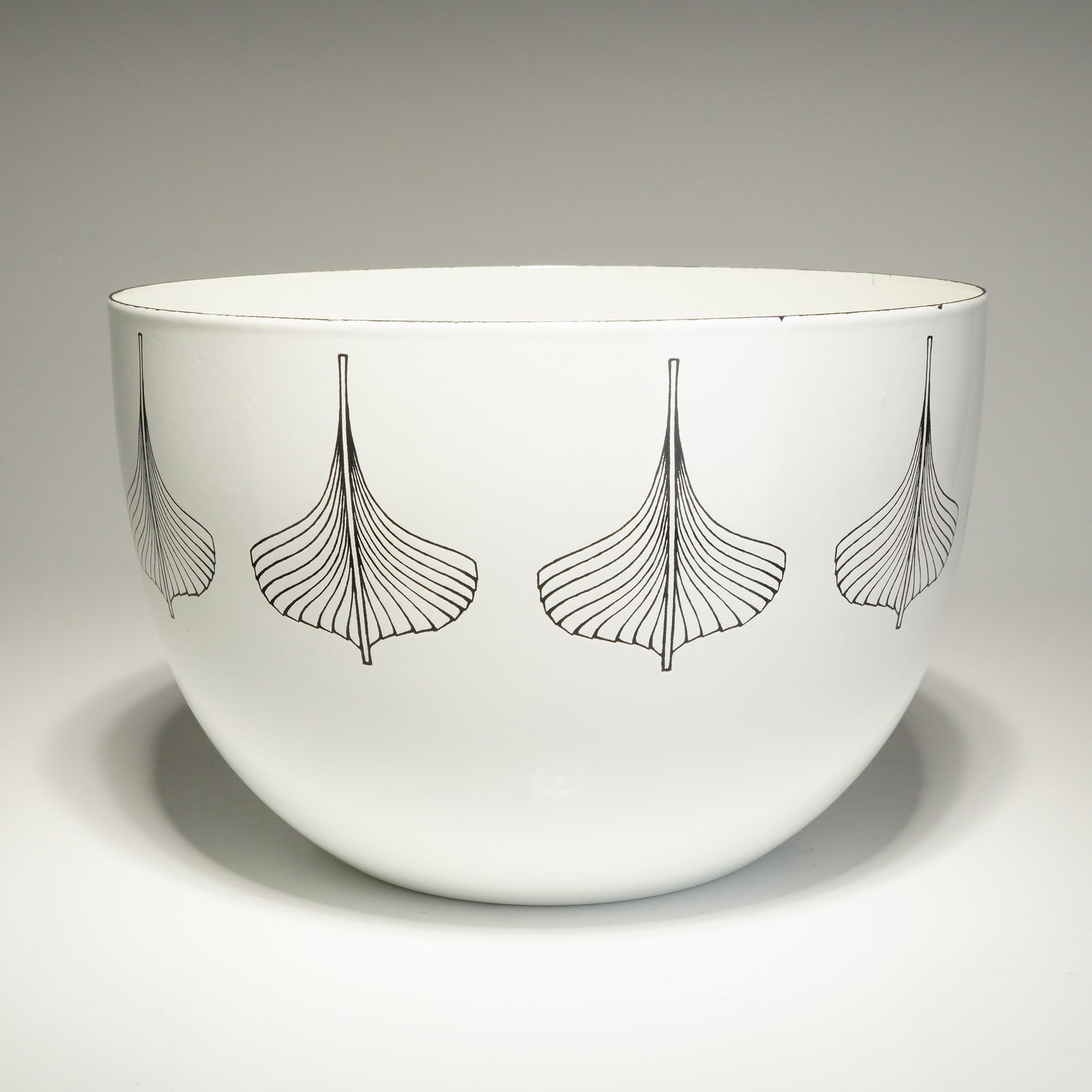 Finel Arabia Finland Kaj Franck Enameled Bowl: This mid-century modern bowl, crafted from white enamel on metal, was designed by Kaj Franck (Finnish, 1911-1989) for Finel, a division of Arabia Finland. The exterior showcases a repeating pattern of
