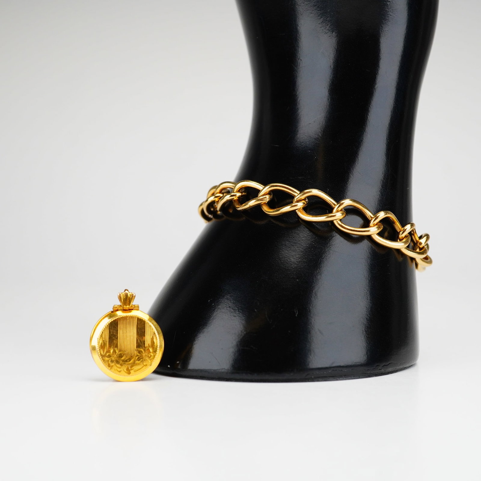 2pc Gold-Filled Locket and Chain Bracelet: This lot includes a 12 karat gold-filled round locket engraved with a floral motif and a 1/20 12 karat gold-filled oval link chain bracelet. Dimensions: 7"L x 0.5"H Weight: 14.72 g
